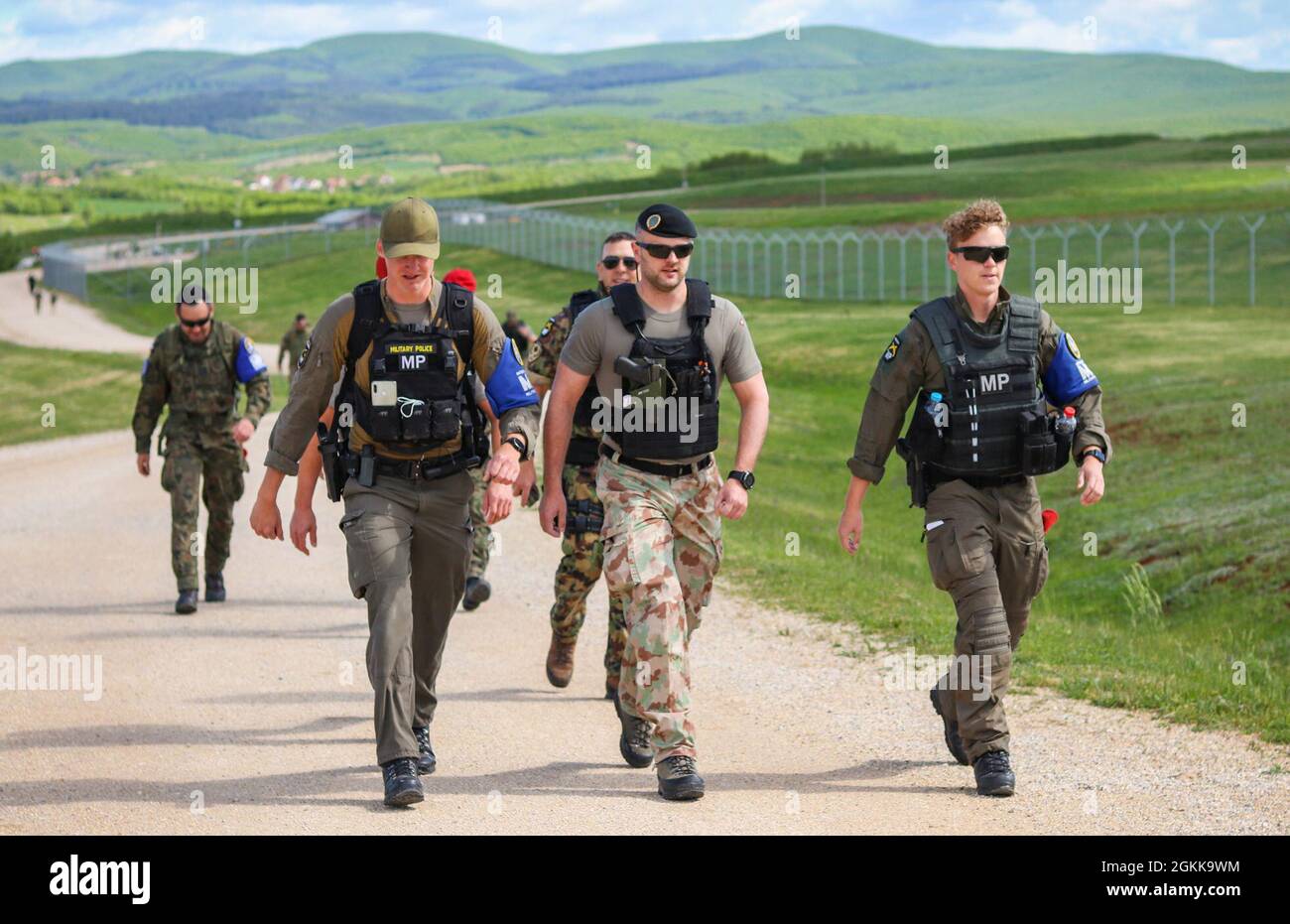 Swiss and Austrian Army military police soldiers assigned to the NATO-led Kosovo Force march together during an MP ruck march at Camp Bondsteel, Kosovo, on May 14, 2021. MPs from across KFOR came together to celebrate National Police Appreciation Week. The week of joint cooperation and training included weapons qualification, obstacle courses, a ruck march and a barbeque. Stock Photo