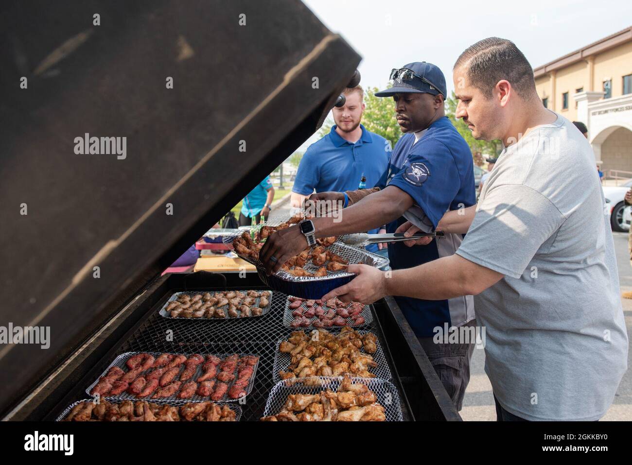 Tech. Sgt. Joe Perkins, 51st Security Forces Squadron contingency operations section chief, middle, and Master Sgt. Alejandrino Herrera, 51st SFS commander support staff superintendent, right, remove cooked meats from the grill during the Police Week Morale Cookout at Osan Air Base, Republic of Korea, May 13, 2021. The cookout was open to all base personnel and host nationals, and finished off the week full of events with an afternoon of morale building and relaxation. Stock Photo