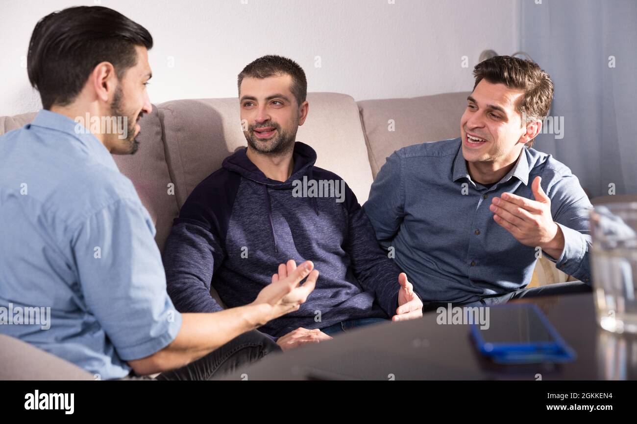 Three males having fun talking on couch Stock Photo