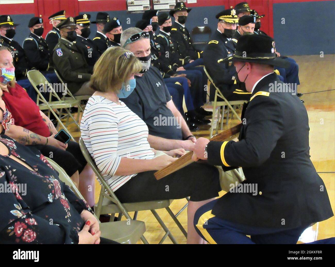 New York Army National Guard Capt. Raymond Campbell, the commander of A Troop, 2nd Squadron, 101st Cavalry, presents an American flag to Julie Kelly, the mother of Spc Justin Grennell during a memorial service at the New York State Armory in Geneva, New York on May 15, 2021. Grennell passed away on March 11 after he was found unresponsive in his hotel room while serving as part of the National Guard security mission in the city. Stock Photo