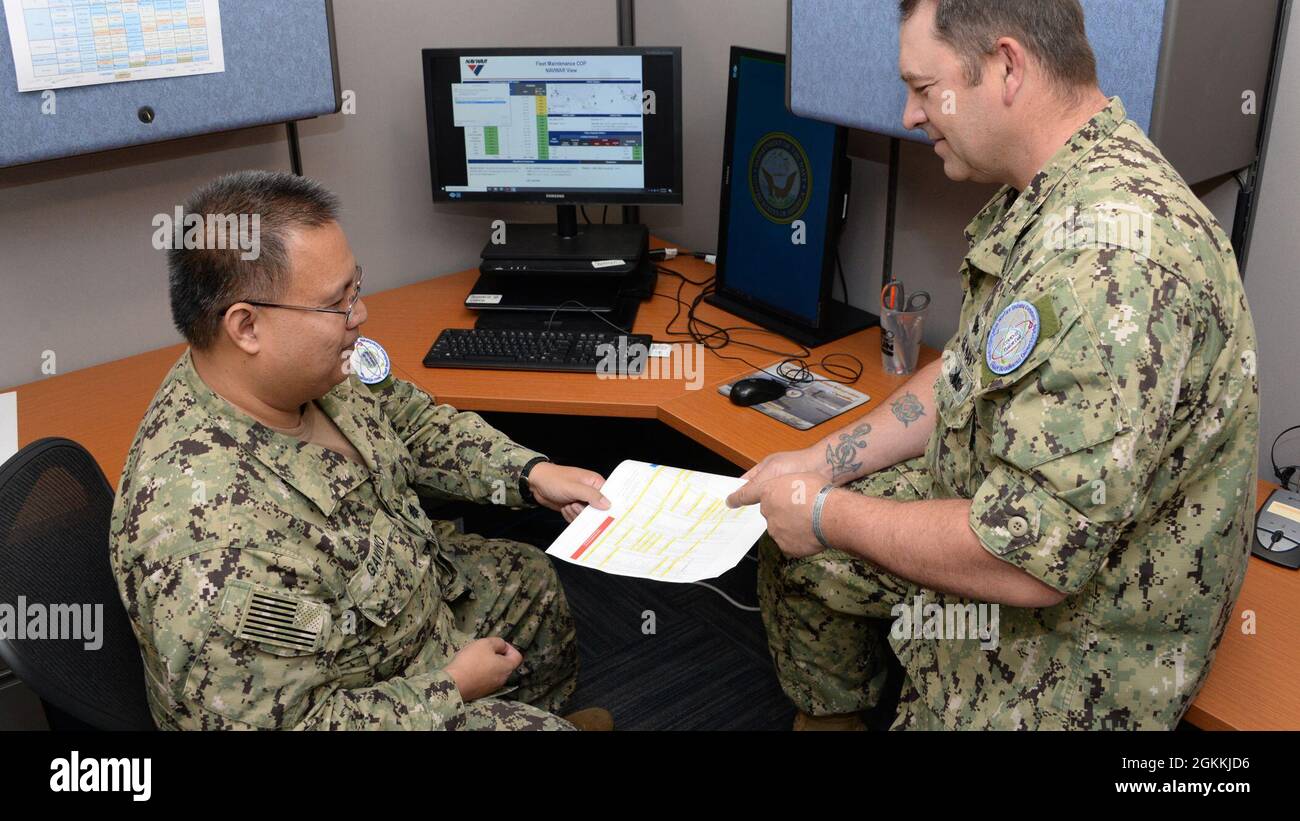 210518-N-UN340-002 SAN DIEGO (May 18, 2021) U.S. Navy CDR Christopher Gavino, left, and Senior Chief Cryptologic Specialist (Maintenance) J.D. Henry, both assigned to Naval Information Warfare Systems Command (NAVWAR) Fleet Readiness Directorate 100 update a Fusion Cell brief to inform NAVWAR’s civilian and military leadership on recent COVID-19 impacts.  Gavino and Henry are Fusion Cell Plankowners who created the virtual data repository to acquire, fuse, interpret and distribute information to track NAVWAR personnel, resources, programs and efforts impacted by the COVID-19 pandemic. Stock Photo