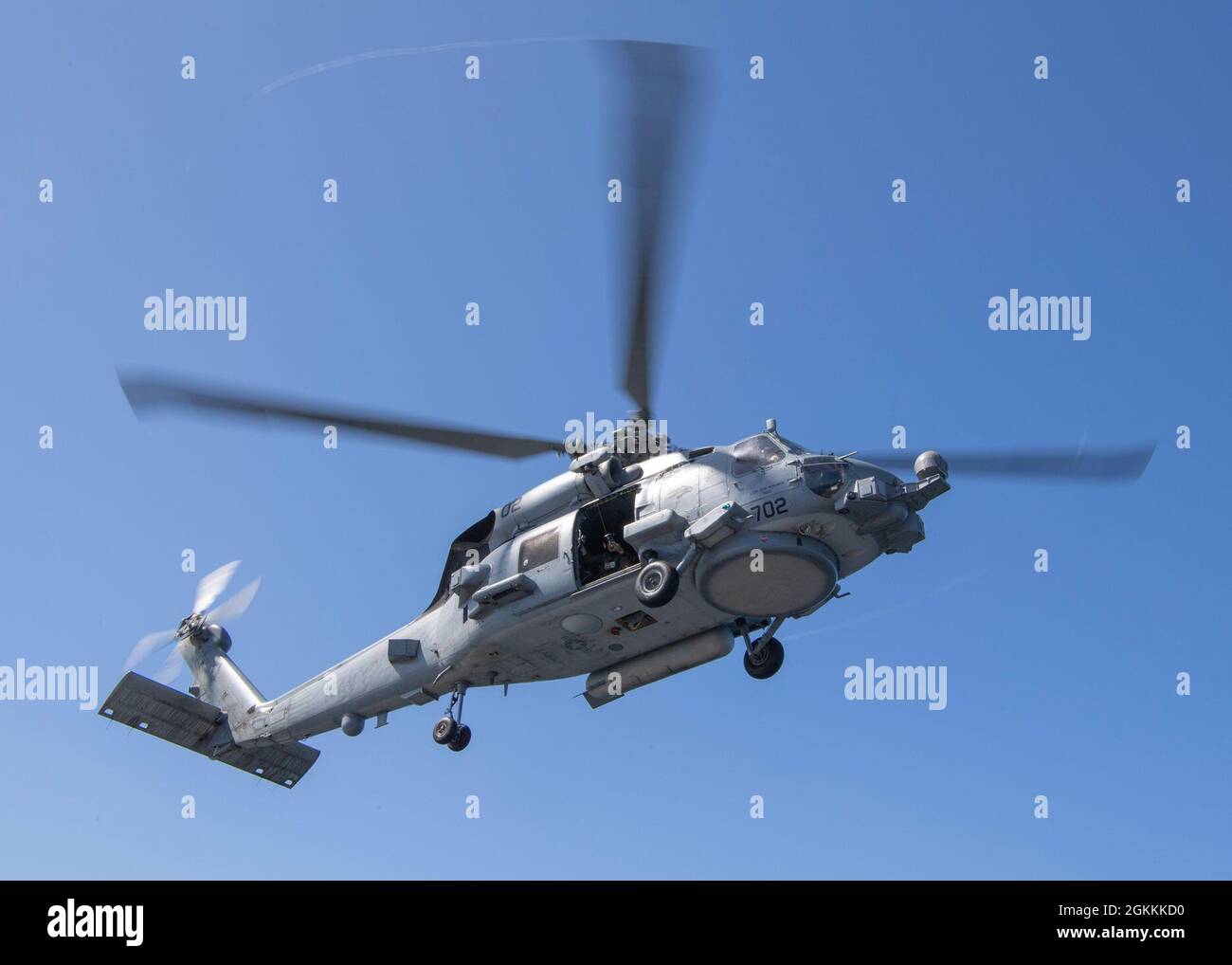 PACIFIC OCEAN (May 18, 2021) An MH-60R Sea Hawk, assigned to the “Wolf Pack” of Helicopter Maritime Strike Squadron (HSM) 75, hovers above the flight deck of the Ticonderoga-class guided-missile cruiser USS Bunker Hill (CG 52) during helicopter in-flight refueling training May 18, 2021. Bunker Hill, part of the Theodore Roosevelt Carrier Strike Group, is on a scheduled deployment conducting routine operations in U.S. 3rd Fleet. Stock Photo
