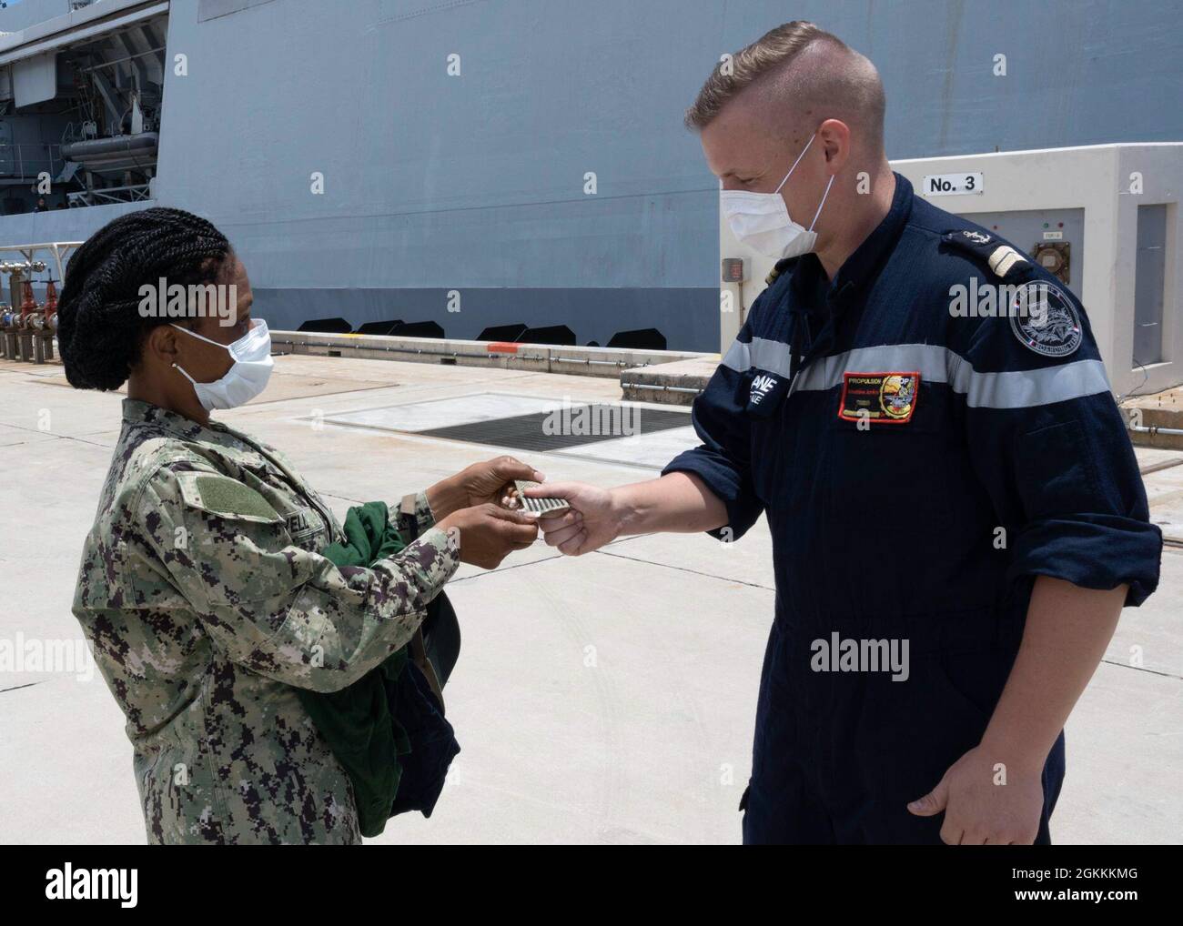 WHITE BEACH, Japan (May 18, 2021) Lt. Donna Powell, Commander, Fleet  Activities Okinawa port operations officer and liaison officer gives her US  Navy jack shoulder patch to an officer from French navy