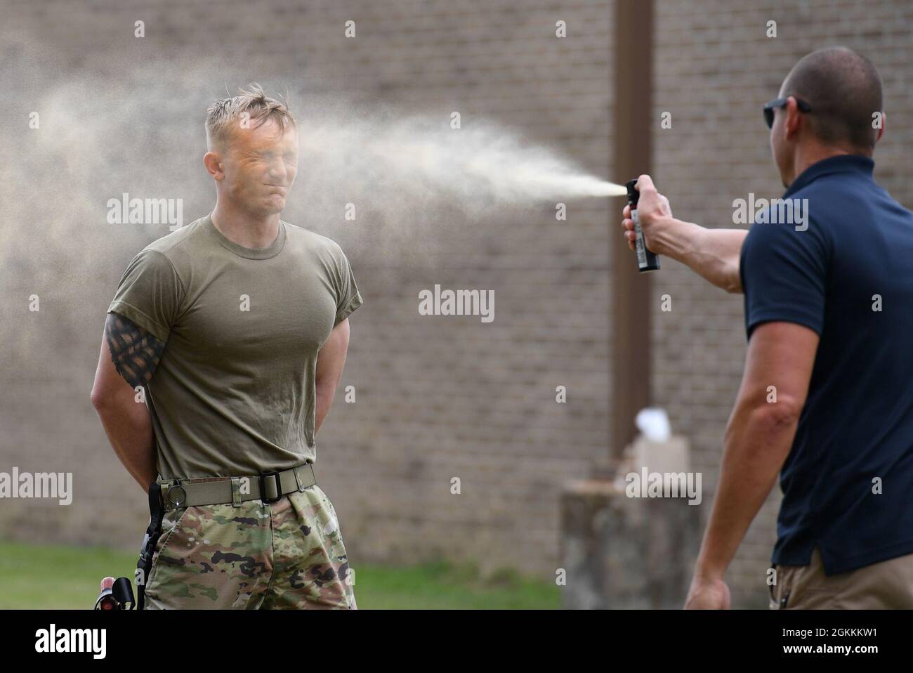 Justin Depew, 81st Security Forces Squadron unit trainer, sprays oleoresin capsicum on U.S. Air Force Airman 1st Class Levi Rainbolt, 81st SFS installation entry controller, as he participates in OC spray training at Keesler Air Force Base, Mississippi, May 18, 2021. The training is a required one-time exposure of the OC spray for all Security Forces members. Stock Photo