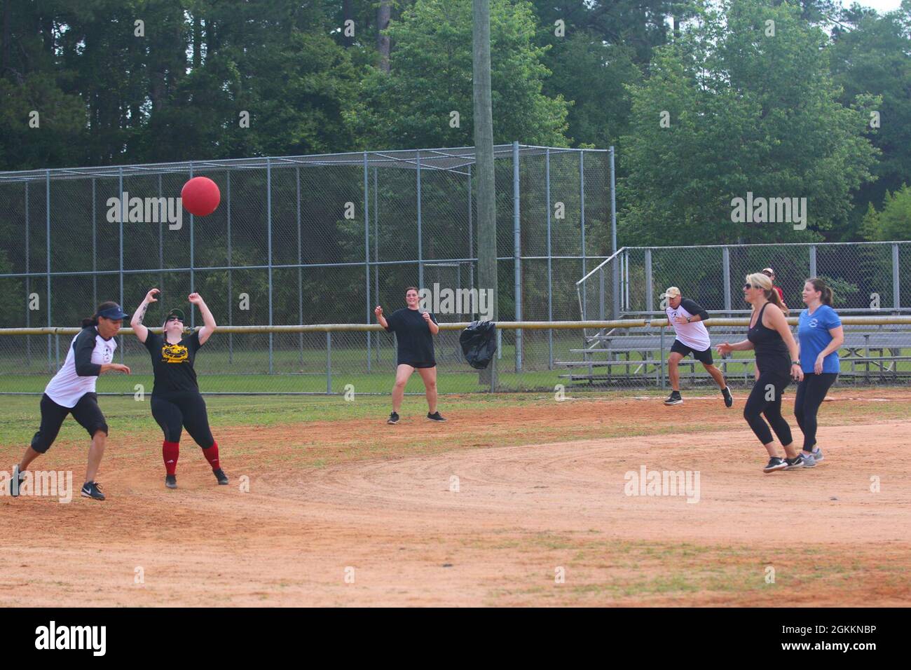 Army spouse Kelli Johnson attempts to catch a kickball as another player rounds a bases during a
