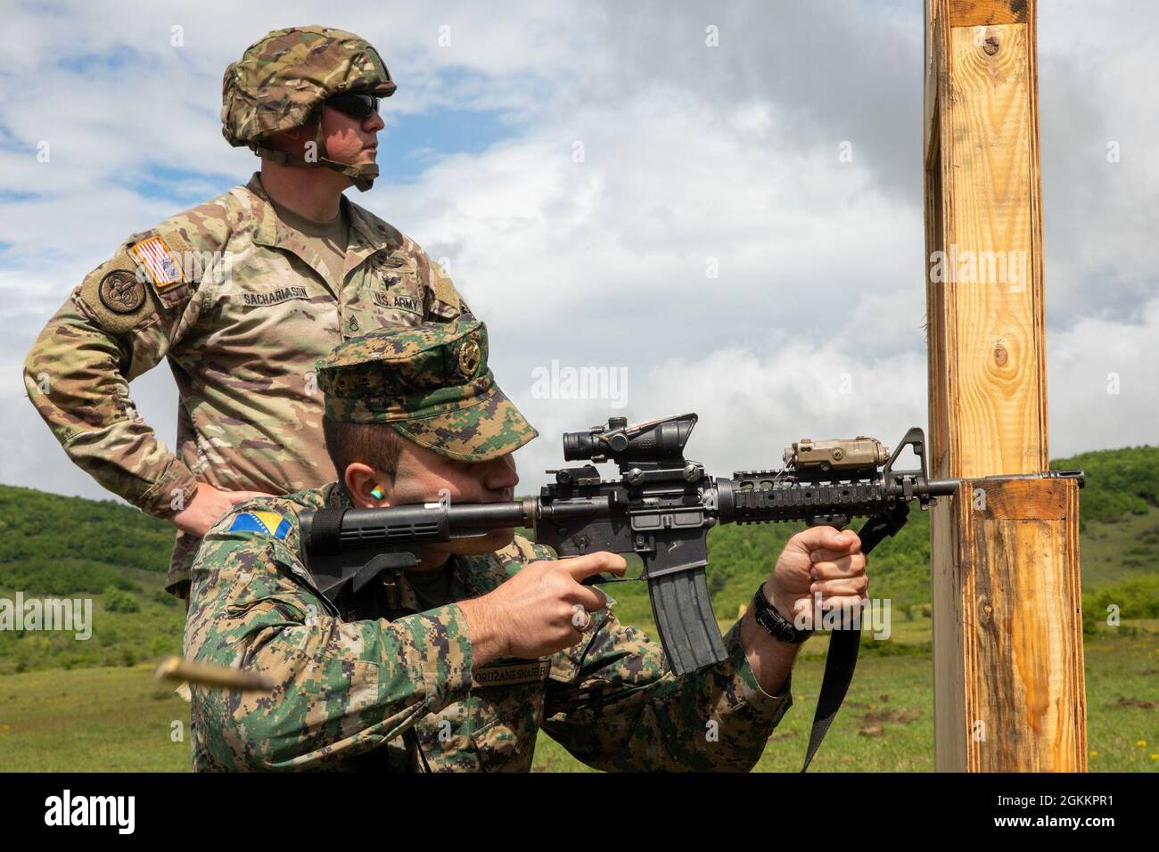 U.S. Army Staff Sgt. Justin Sachariason (left), a Soldier assigned to the Florida Army National Guard’s 2nd Battalion, 124th Infantry Regiment, 53rd Infantry Brigade Combat Team, watches as 1st Lt. Almir Sarač, a soldier from the Armed Forces of Bosnia and Herzegovina (AFBiH), shoots the M4A1 Carbine at Manjača Training Area, Bosnia and Herzegovina (BiH), May 19, 2021. The 2-124th Soldiers will work alongside the AFBiH in a joint training exercise called Immediate Response 21, which supports DEFENDER-Europe 21. DEFENDER-Europe 21 is a prime example of U.S. forces working together closely with Stock Photo