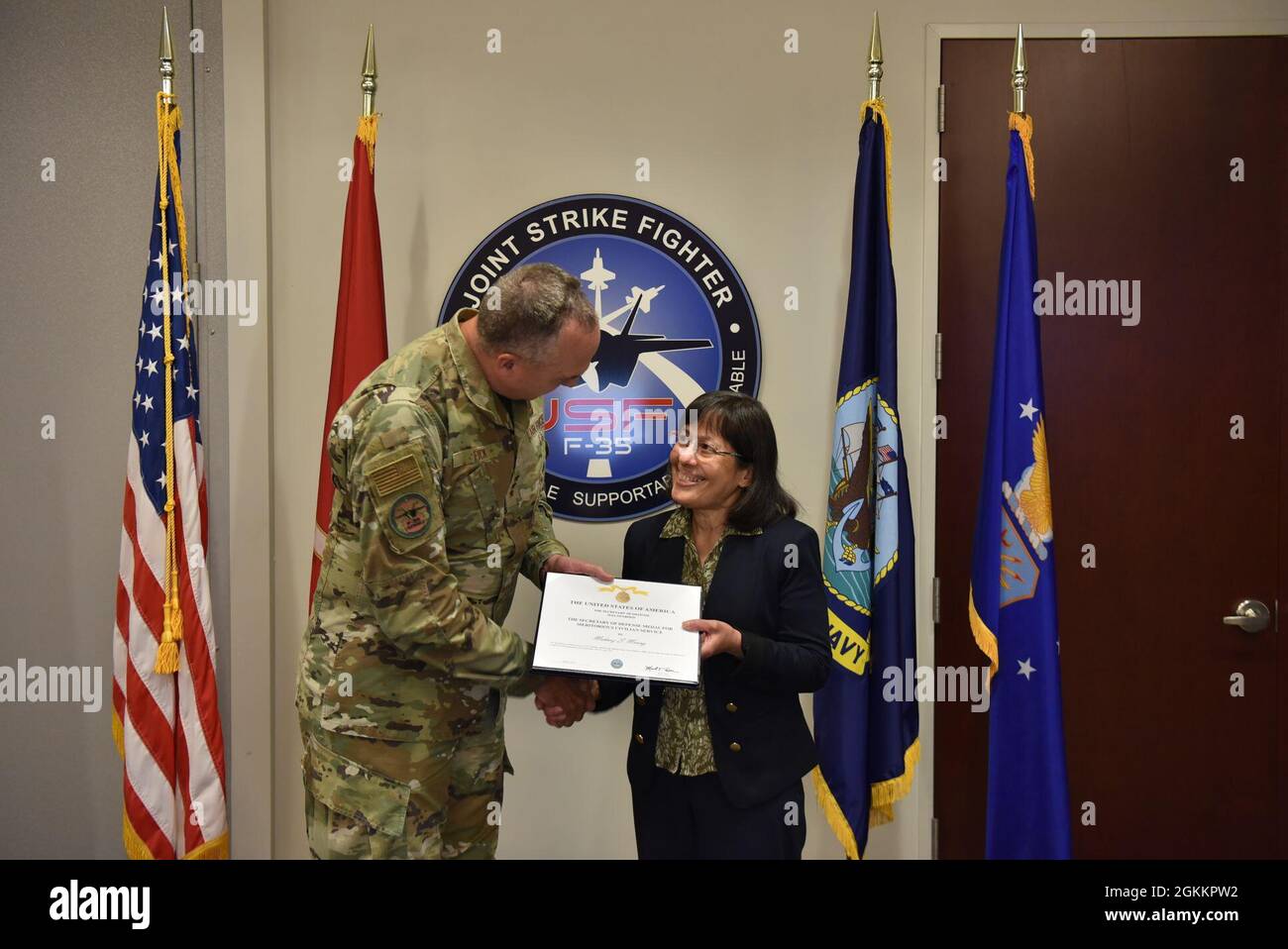 Lt. Gen. Eric Fick, F-35 Joint Program Executive Officer, presents Mahnaz Maung, F-35 Systems Engineering Transformation Lead, with the Secretary of Defense Medal for Meritorious Civilian Service certificate during a semi-virtual all hands ceremony at the program headquarters in Arlington, Va. The F-35 Joint Program Office is the Department of Defense's focal point for the 5th generation strike aircraft for the Navy, Air Force, Marines, and our allies. The F-35 is the premier multi-mission, 5th generation weapon system. Its ability to collect, analyze and share data is a force multiplier that Stock Photo