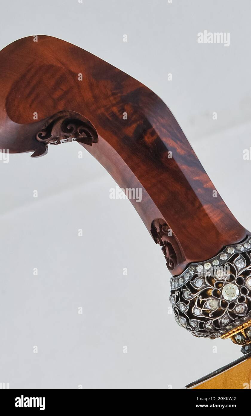 A keris handle or hilt made of selected wood decorated with carvings and gemstones. Stock Photo
