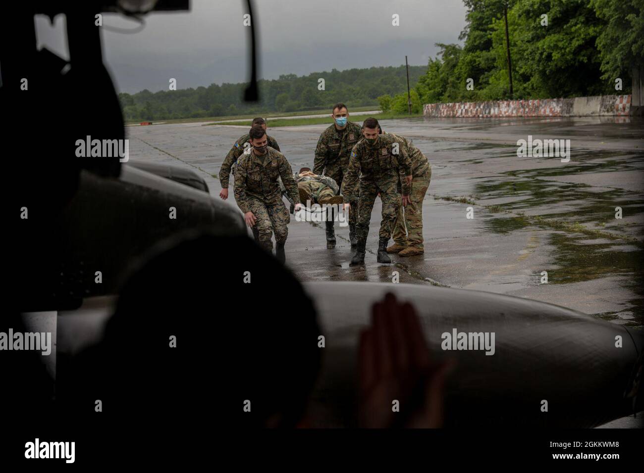 (Tuzla International Airport, Bosnia) - A crew chief with the 1st Cavalry waves the Bosnian soldiers to escort the litter into the active UH-60L Blackhawk during DEFENDER-Europe 21, at Tuzla International Airport, Bosnia & Herzegovina, May 20, 2021. (Army National Guard photos by Spc. Jordan Arnold) Stock Photo