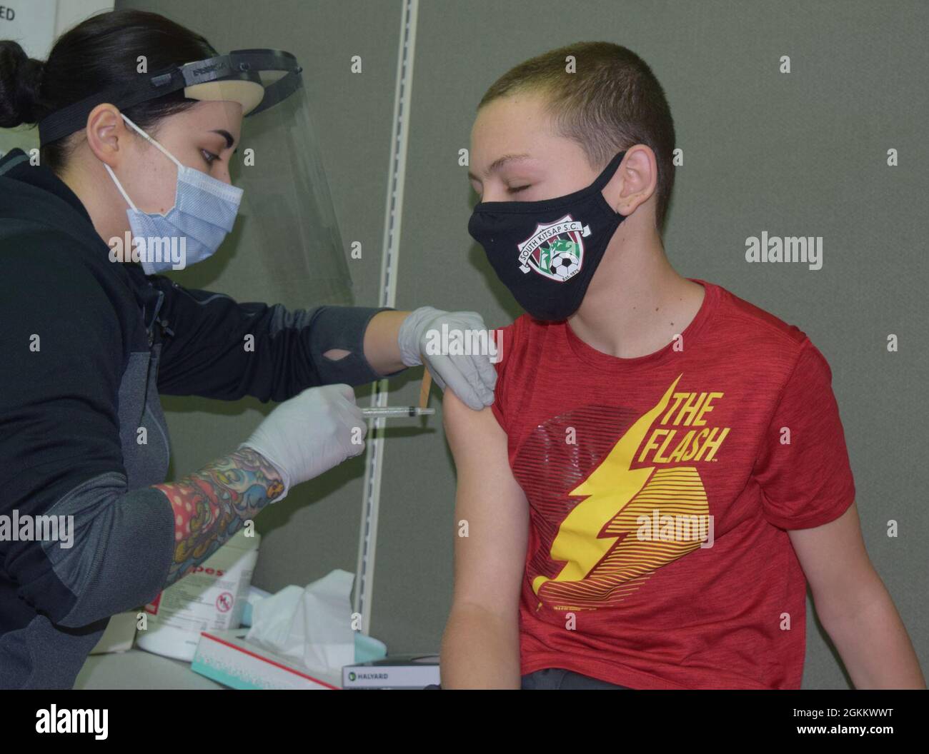 Done in a blink…Samuel Stockton, 14-year old son of Naval Hospital Bremerton Command Master Chief Rob Stockton, is administered his first dose of Pfizer COVID-19 vaccine. NHB is offering COVID-19 vaccinations to eligible beneficiaries age 12 and older. The Pfizer COVID-19 vaccine is available on a walk-in basis in NHB’s Urgent Care Clinic from 3:30 pm to 7 p.m. during the week and 9 a.m. to 7 p.m. on weekends. The Immunization Clinic is also accepting walk-ins during the week. A parent or guardian must accompany those under the age of 18. Appointments can also be made for the COVID-19 vaccinat Stock Photo