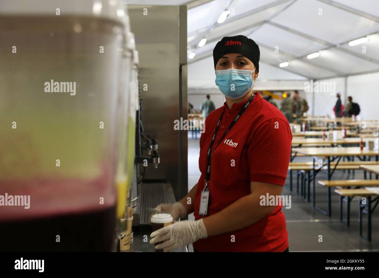 An Albanian food service worker pours a cup of coffee for a guest at a military dining facility May 21,2021, where Albanians and Americans work hand in hand to bring quality food to the American military personnel currently taking part in DEFENDER-Europe 21 training exercises  at Kucove Air Base, in Kucove/Berat, Albania.  DEFENDER-Europe 21 is a large-scale U.S. Army-led exercise designed to build readiness and interoperability between the U.S., NATO allies and partner militaries. This year, more than 28,000 multinational forces from 26 nations will conduct nearly simultaneous operations acro Stock Photo
