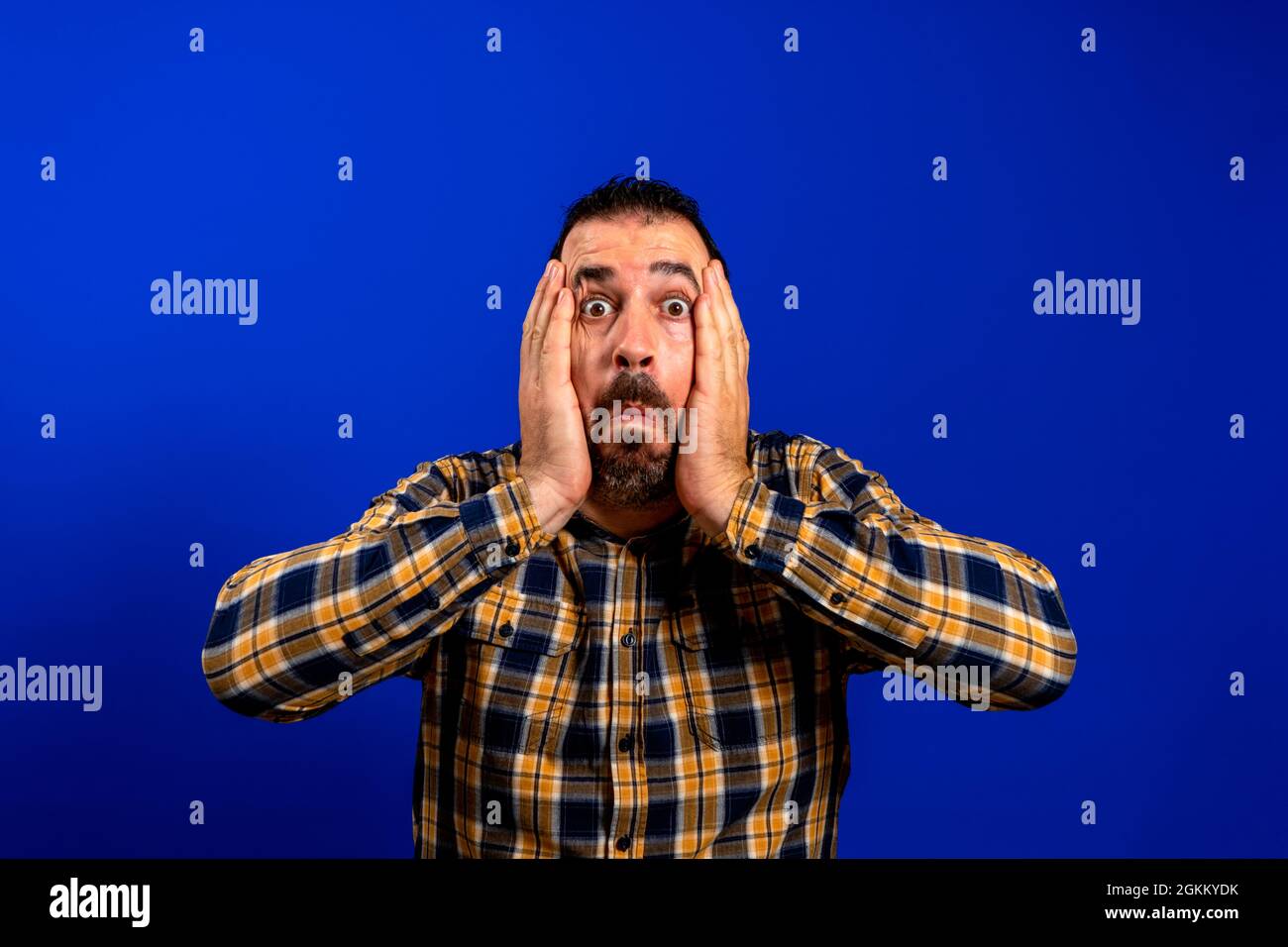 Young man with a frightened pose over blue monochrome background Stock Photo