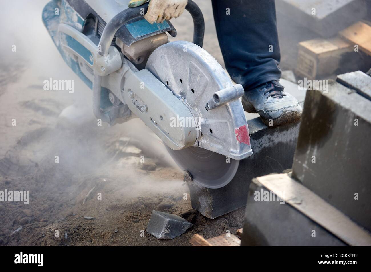 A worker with a circular saw cuts a curb stone close-up. Stock Photo