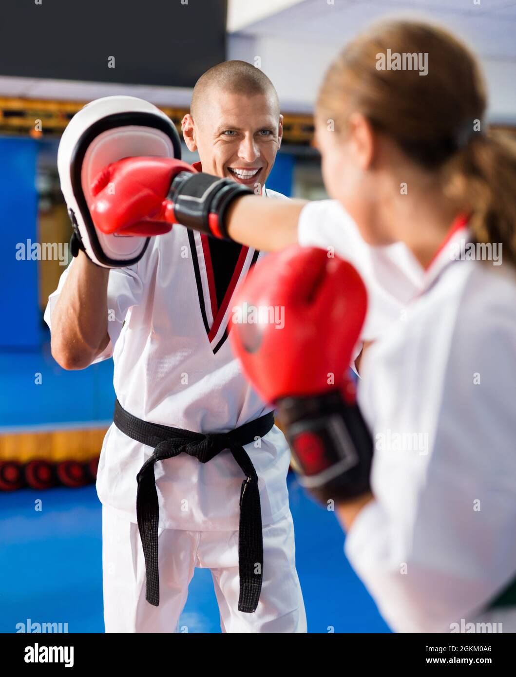 Young woman practicing boxing punches in pair with instructor Stock Photo