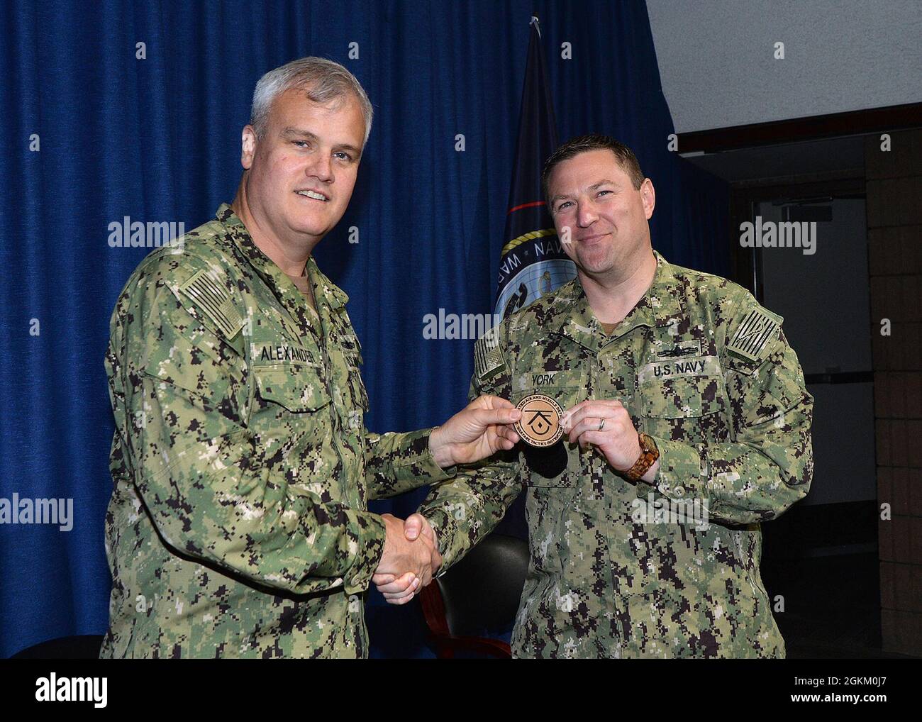 Rear Adm. Christopher Alexander, commander of Naval Surface and Mine Warfighting Development Center (SMWDC) hands an Integrated Air and Missile Defense (IAMD) Warfare Tactics Instructor (WTI) patch to and congratulates Lt. Cmdr. Jeffrey York during a WTI graduation ceremony held onboard Naval Station San Diego May 21st. Stock Photo
