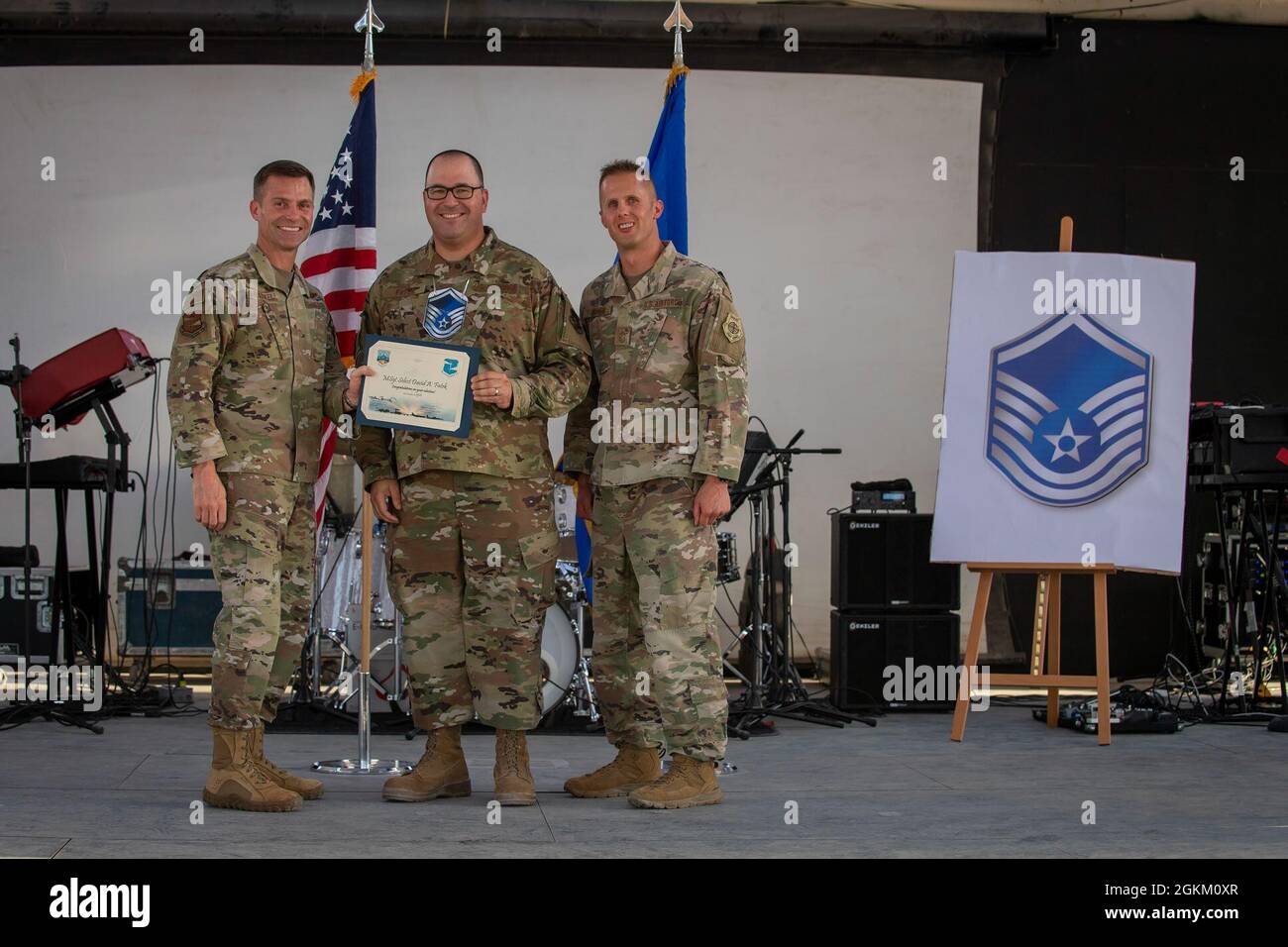 U.S. Air Force Brig. Gen. Larry R. Broadwell, 380th Air Expeditionary Wing commander (AEW), and Chief Master Sgt. Joshua J. Wiener, 380th AEW command chief, pose with Tech. Sgt. David Fatek, Air Force Central Command Band (AFCENT Band), at Al Dhafra Air Base (ADAB), United Arab Emirates, May 21, 2021. Fatek is currently touring with the AFCENT Band and is an honorary team ADAB technical sergeants that was selected for promoted to master sergeant this year. Stock Photo