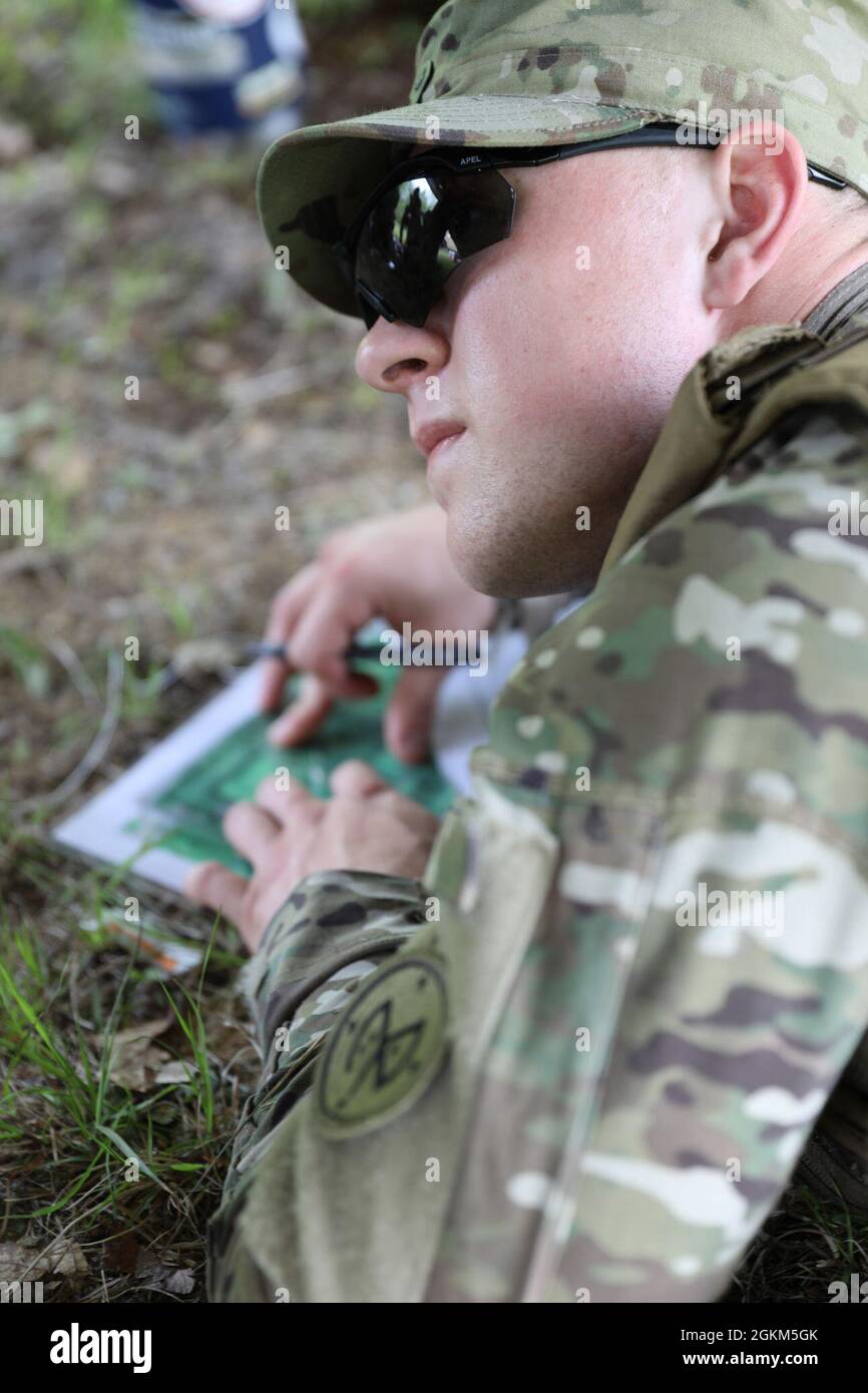 New York Army National Guard Spc. Austin Manville, an infantryman assigned to Charlie Troop, 2nd Squadron,101st Cavalry Regiment, plots points on a map during a land navigation exercise as part of the squadron's Best Warrior Competition in Ellicottville, New York on May 22. Manville placed first in the competition's Soldier category, which tested physical fitness and endurance, military knowledge and bearing, and basic Soldier skills. Stock Photo