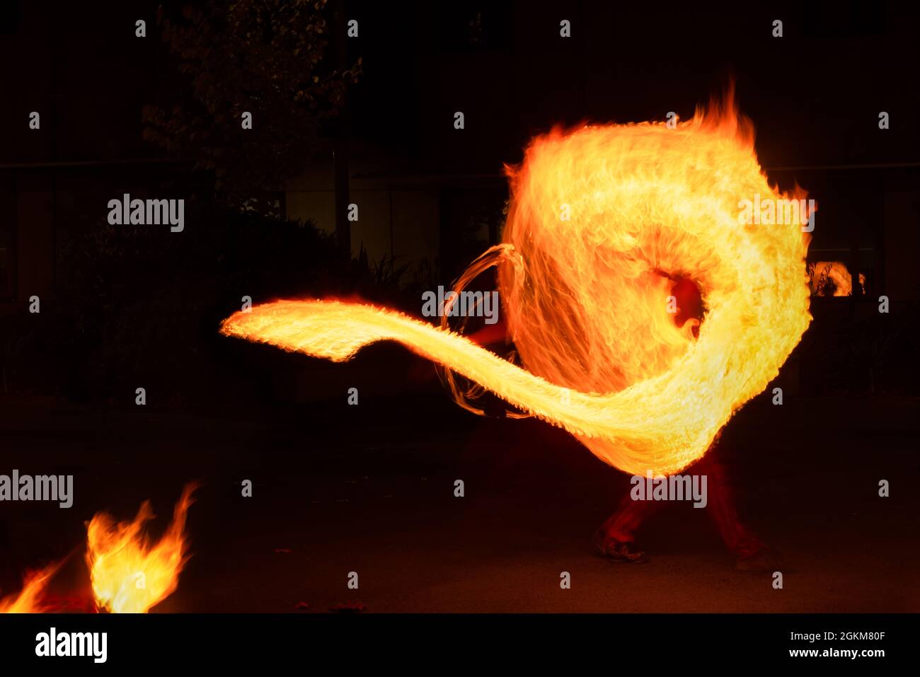 Artist juggling with burning poi at fire performance. Long exposure