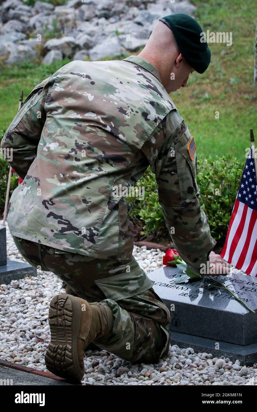 A Green Beret assigned to 3rd Special Forces Group (Airborne) places a rose on a Soldiers memorial stone during the 3 SFG (A) memorial walk ceremony at Fort Bragg, NC, May 25, 2021. Gold star family members, friends and fellow Soldiers gathered in remembrance of Soldiers who have died while deployed and honored their memory by placing a single rose on top of their memorial stone. Stock Photo