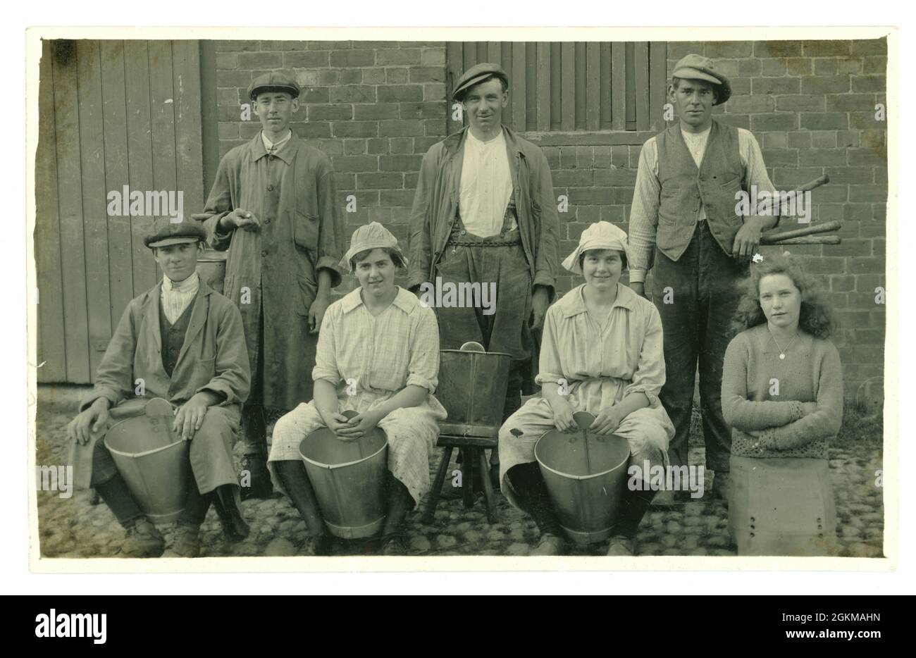 Original WW1 era postcard of group of farm hands and dairy maids, probably land girls, farmer's daughter, with milk pails, circa 1917, U.K. Stock Photo