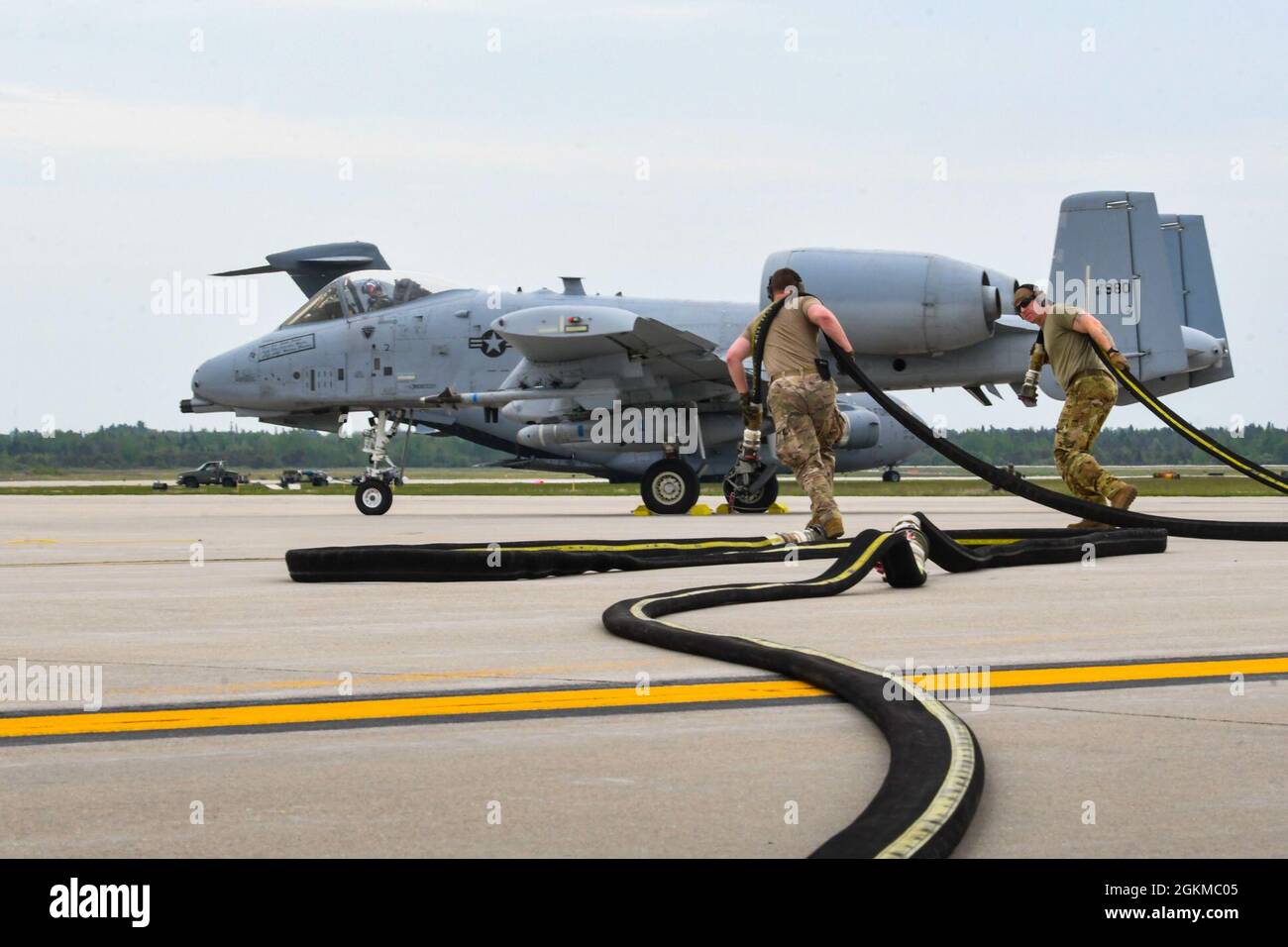 Airmen from the 19th Airlift Wing prepare for refueling near a U.S. Air Force A-10 Thunderbolt II at Alpena Combat Readiness Training Center, Michigan, May 25, 2021. The 354th Fighter Squadron worked alongside the 61st and 41st Airlift Squadrons in order to perform integrated combat turns, a rapid turnaround process that allowed A-10s to quickly rearm and refuel during Mobility Guardian 2021 reducing the pilot’s ground time to quickly resume air dominance. Stock Photo
