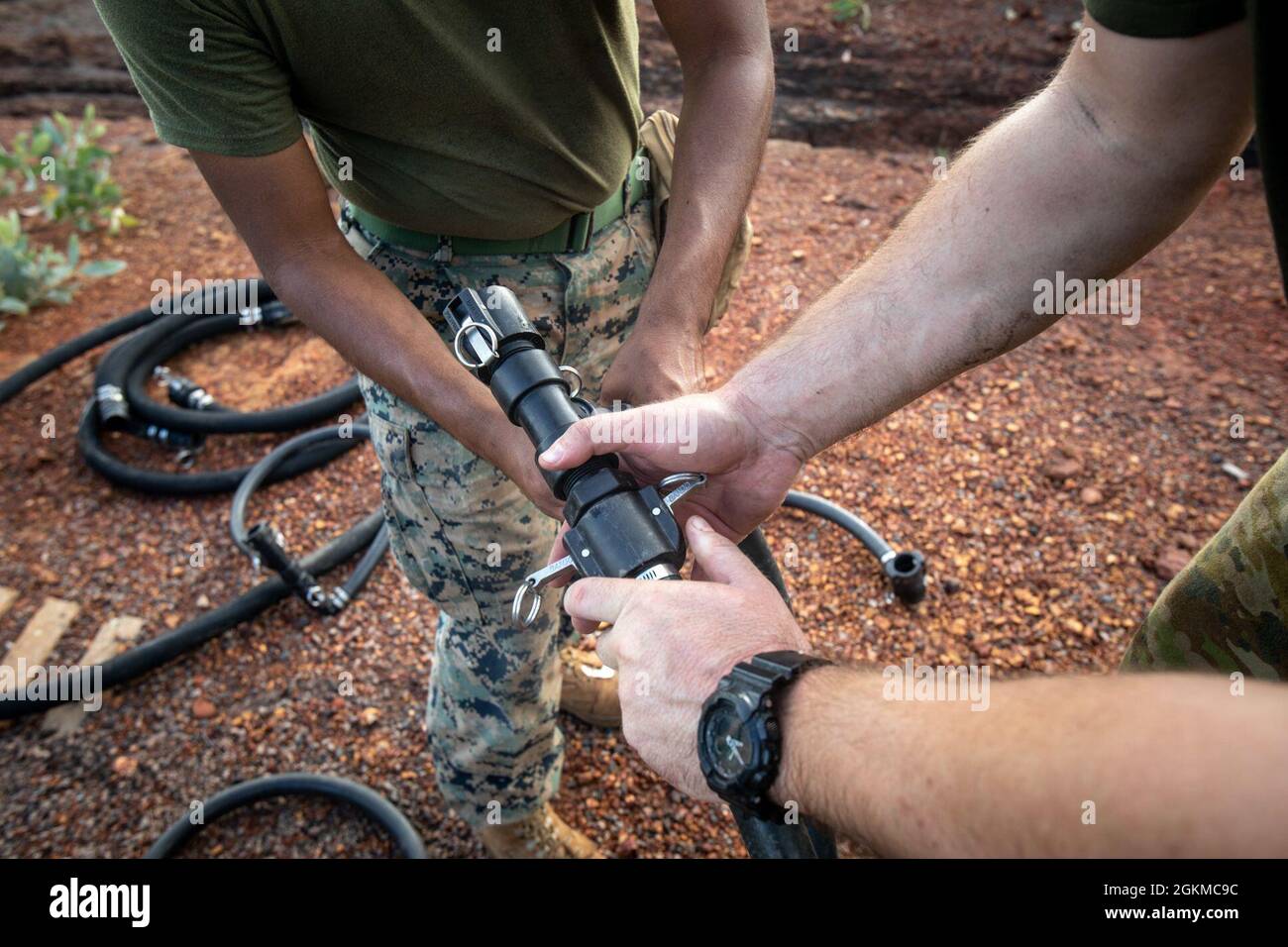 A U.S. Marine and Australian Army soldier connect two hoses while
