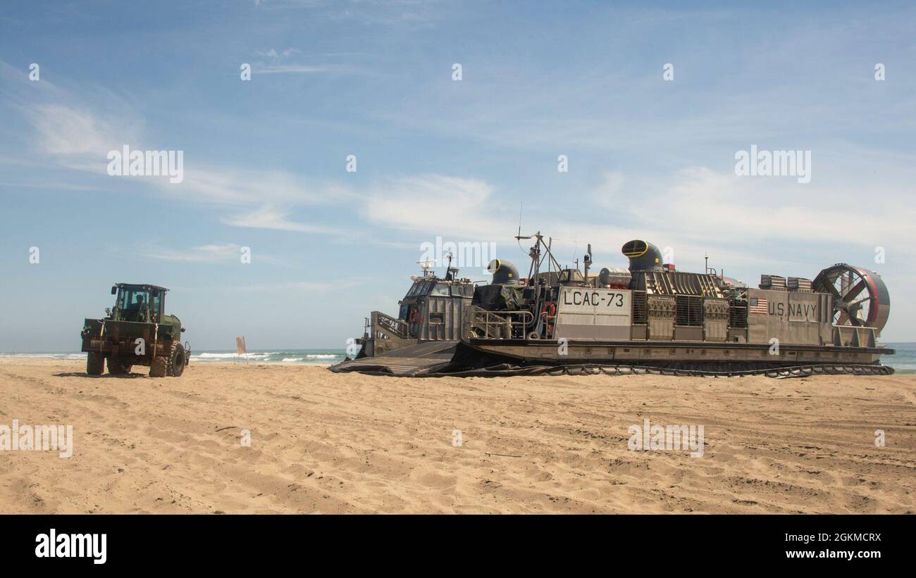 PACIFIC OCEAN (May 25, 2021) U.S. Marine Corps Cpl. Bryan Vargas, from Haslet, Texas, assigned to Combat Logistic Battalion (CLB) 11, drives a Tractor Rubber-tired Articulated steering Multipurpose vehicle (TRAM) 624KR, attached to CLB 11, off of a Landing Craft, Air Cushion (LCAC), attached to Assault Craft Unit (ACU) 5, during amphibious operations, May 25. Sailors and Marines of the Essex Amphibious Ready Group (ARG) and the 11th Marine Expeditionary Unit (MEU) are underway conducting integrated training off the coast of southern California. Stock Photo