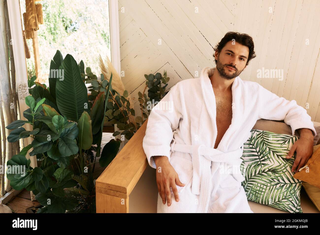 Latin man in white bathrobe rests sitting on couch after baths procedures and wellness at spa resort Stock Photo