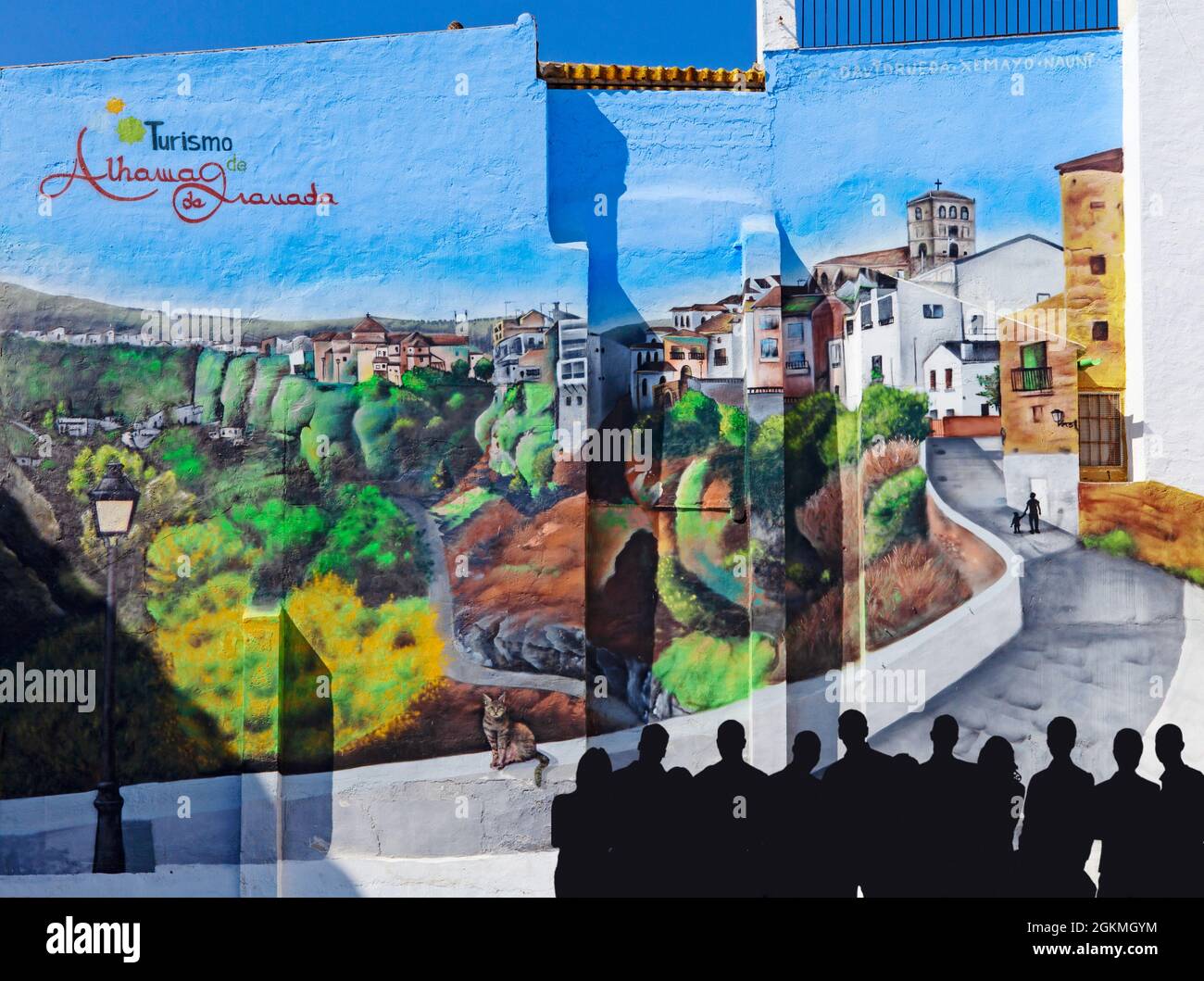 A group of people admiring a gable end mural in the main square in  Alhama de Granada, Andalusia, Spain Stock Photo
