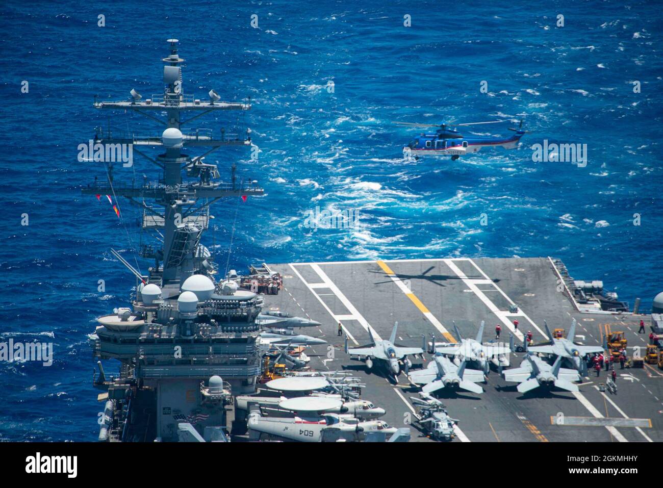 210527-N-VC236-1142 PHILIPPINE SEA (May 27, 2021) A Super Puma (EC-225) helicopter attached to dry cargo and ammunition ship USNS Charles Drew (T-AKE 10) flies above the U.S. Navy’s only forward-deployed aircraft carrier, USS Ronald Reagan (CVN 76), after offloading ordnance during a replenishment-at-sea. Ronald Reagan, the flagship of Carrier Strike Group 5, provides a combat-ready force that protects and defends the United States, as well as the collective maritime interests of its allies and partners in the Indo-Pacific region. Stock Photo