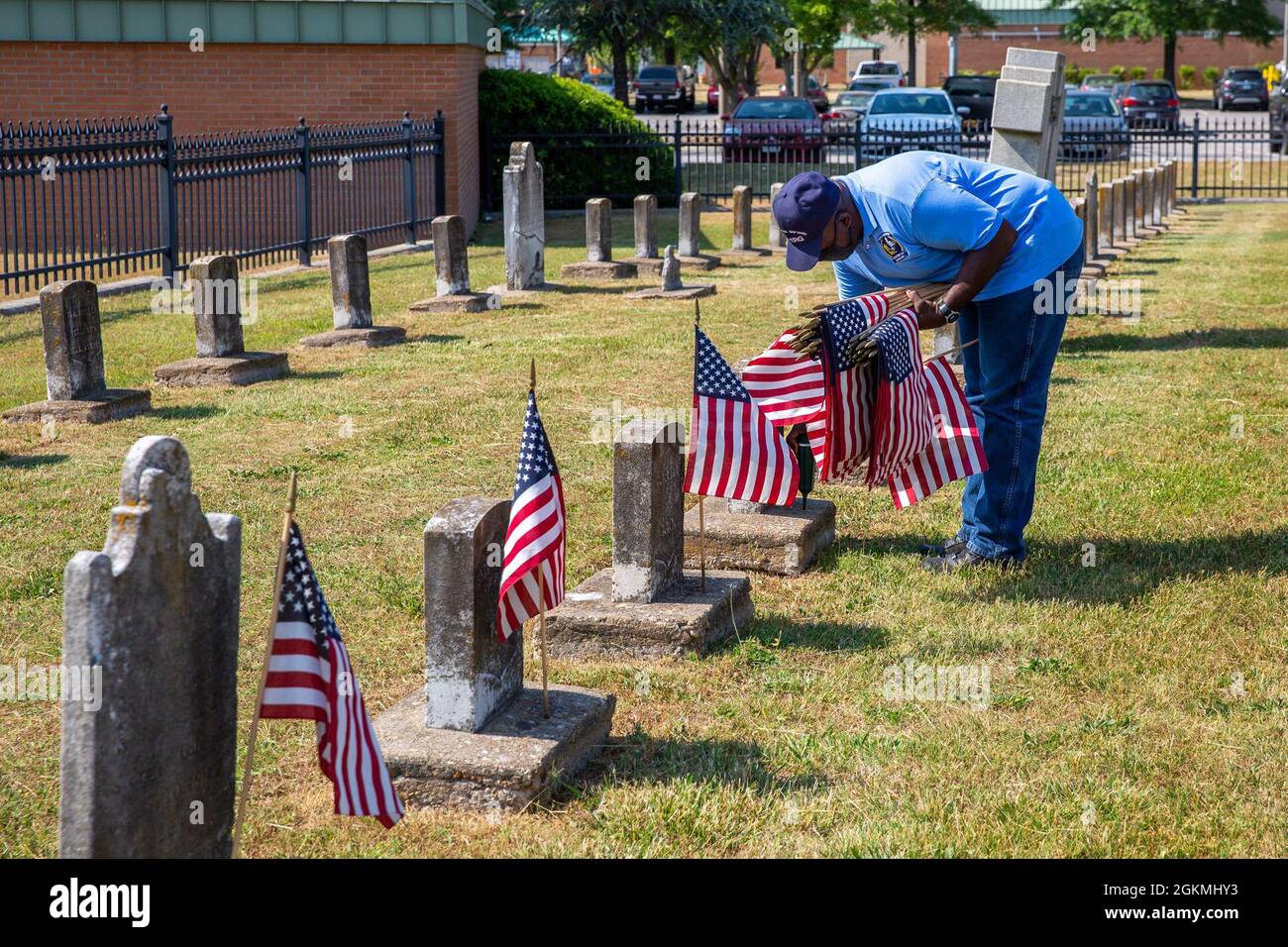 Ricky Burroughs, a member of the Norfolk Naval Shipyard Veteran Employee Readiness Group, places flags on the graves of fallen service members during the annual flag placement ceremony at the Captain Ted Conaway Memorial Naval Cemetery in Naval Medical Center Portsmouth (NMCP) May 27. Stock Photo