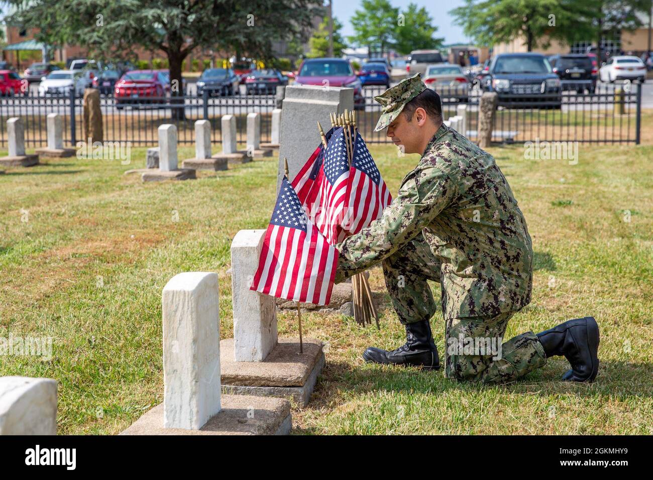 A Sailor stationed at Naval Support Activity Hampton Roads Portsmouth places flags on the graves of fallen service members during the annual flag placement ceremony at the Captain Ted Conaway Memorial Naval Cemetery in Naval Medical Center Portsmouth (NMCP) May 27. Stock Photo