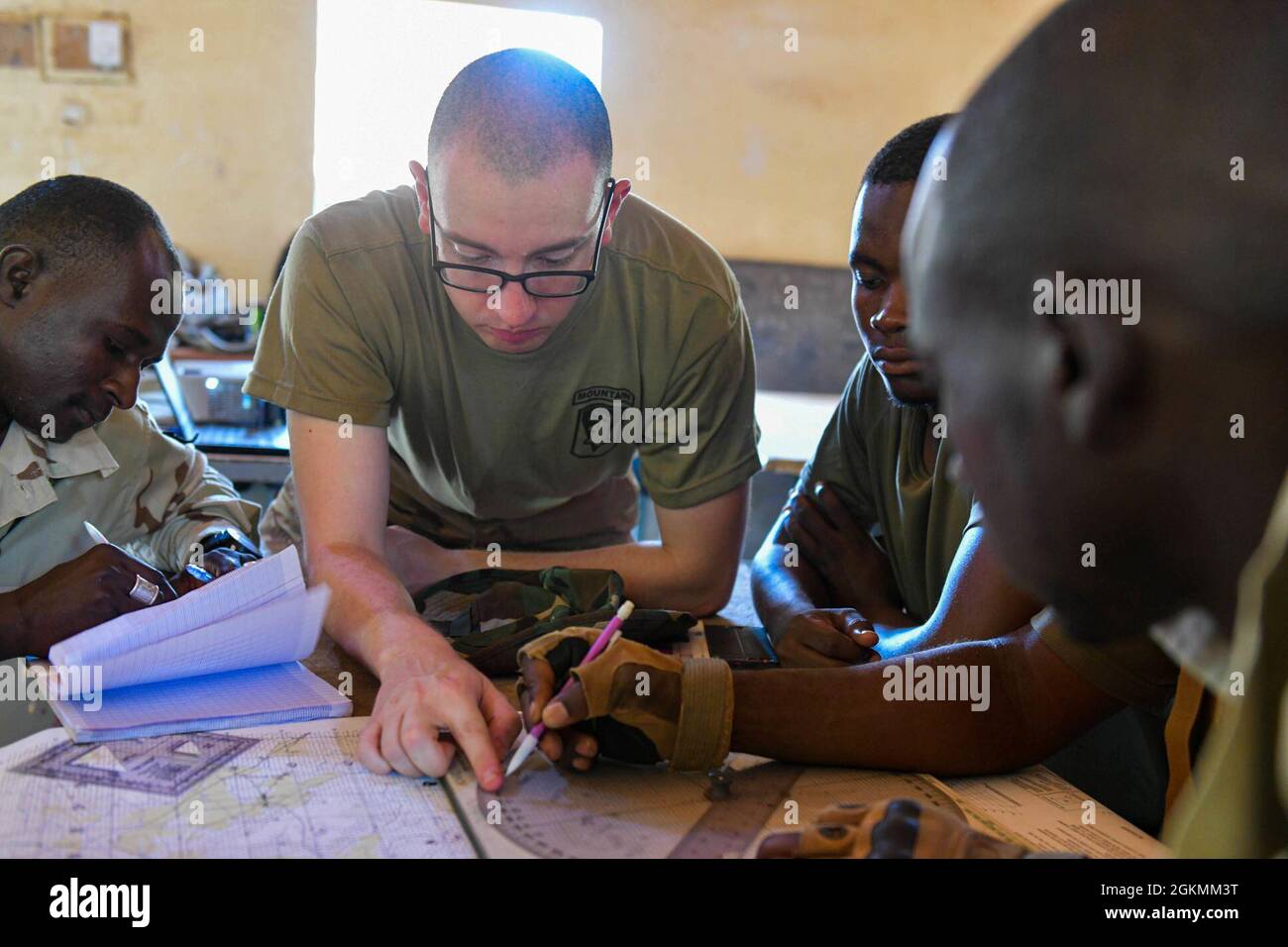 U.S. Army Spc. Brandon Bouchard assigned to Headquarters and Headquarters Company, 1st Battalion, 102nd Infantry, 86th Infantry Brigade Combat Team, in support of Combined Joint Task Force-Horn of Africa (CJTF-HOA), teaches basic mortar map skills at Tondibiah, Niger, May 25, 2021. Soldiers in basic map reading, plotting points, and drawing azimuths. Stock Photo