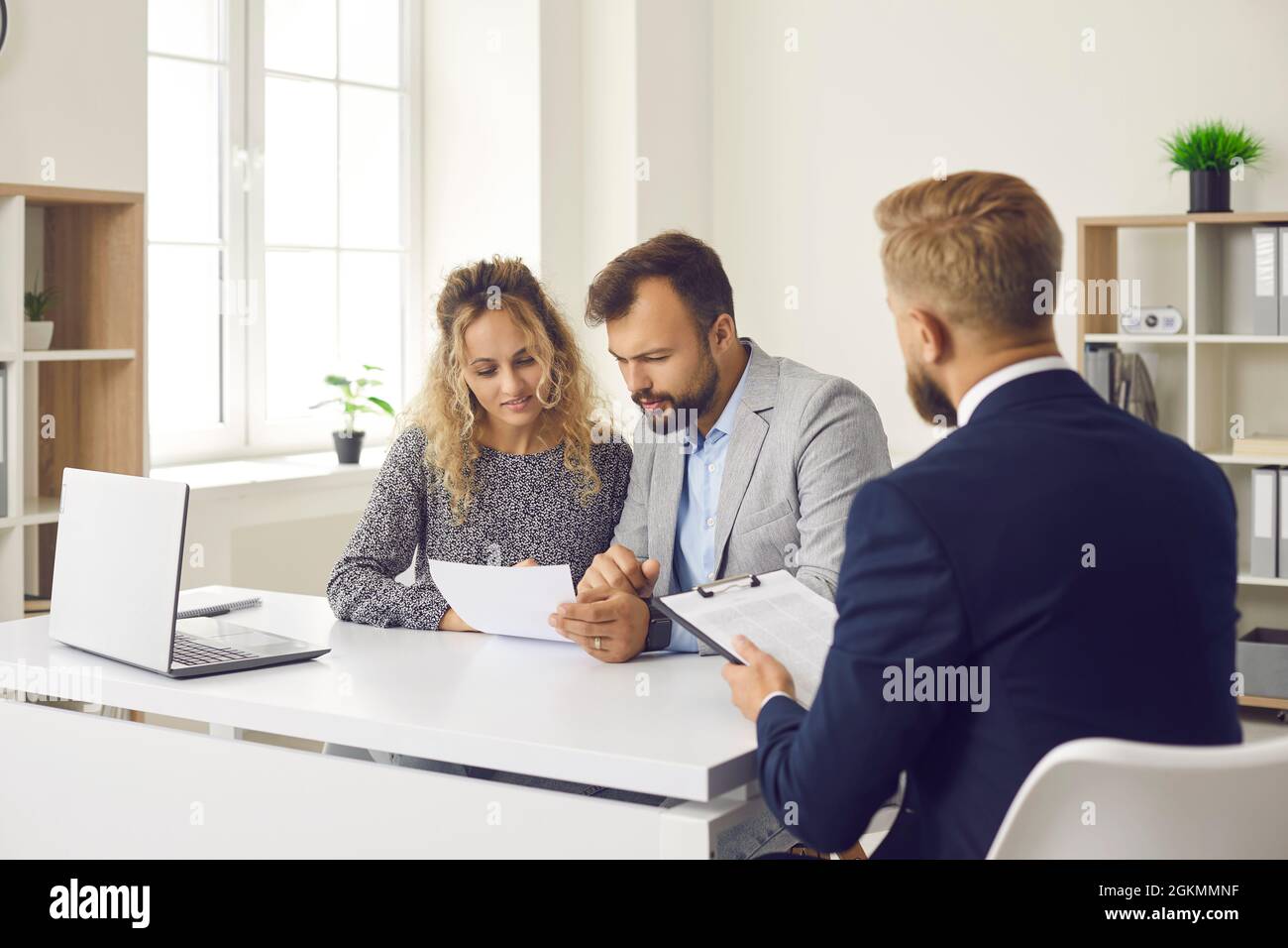 Young couple reading some documents sitting at desk in real estate agent's office Stock Photo
