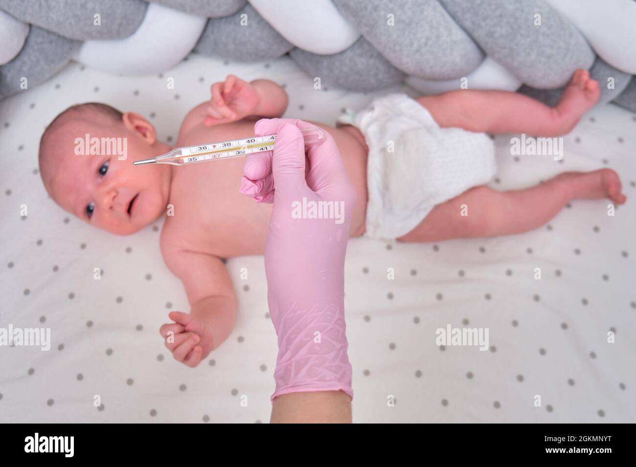 Doctor checks the temperature of the newborn baby with a thermometer. A