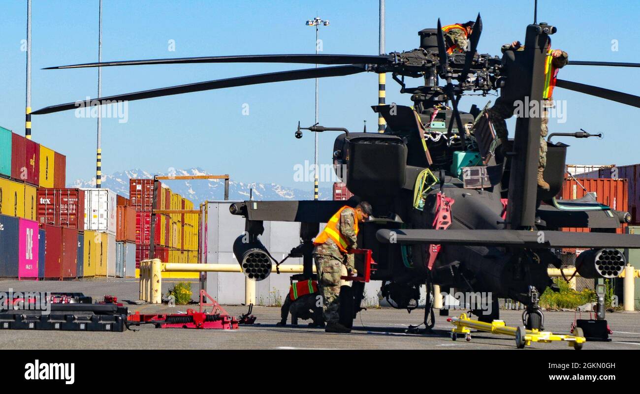 Soldiers assigned to 46th Aviation Support Battalion, 16th Combat Aviation Brigade, prepare an AH-64 attack helicopter for shipment at the Port of Tacoma, Wash., on Jun. 1, 2021.  The unit was preparing aircraft and equipment to be loaded onto a vessel for transport to a training exercise.  Visible in the background are the Olympic mountains. Stock Photo