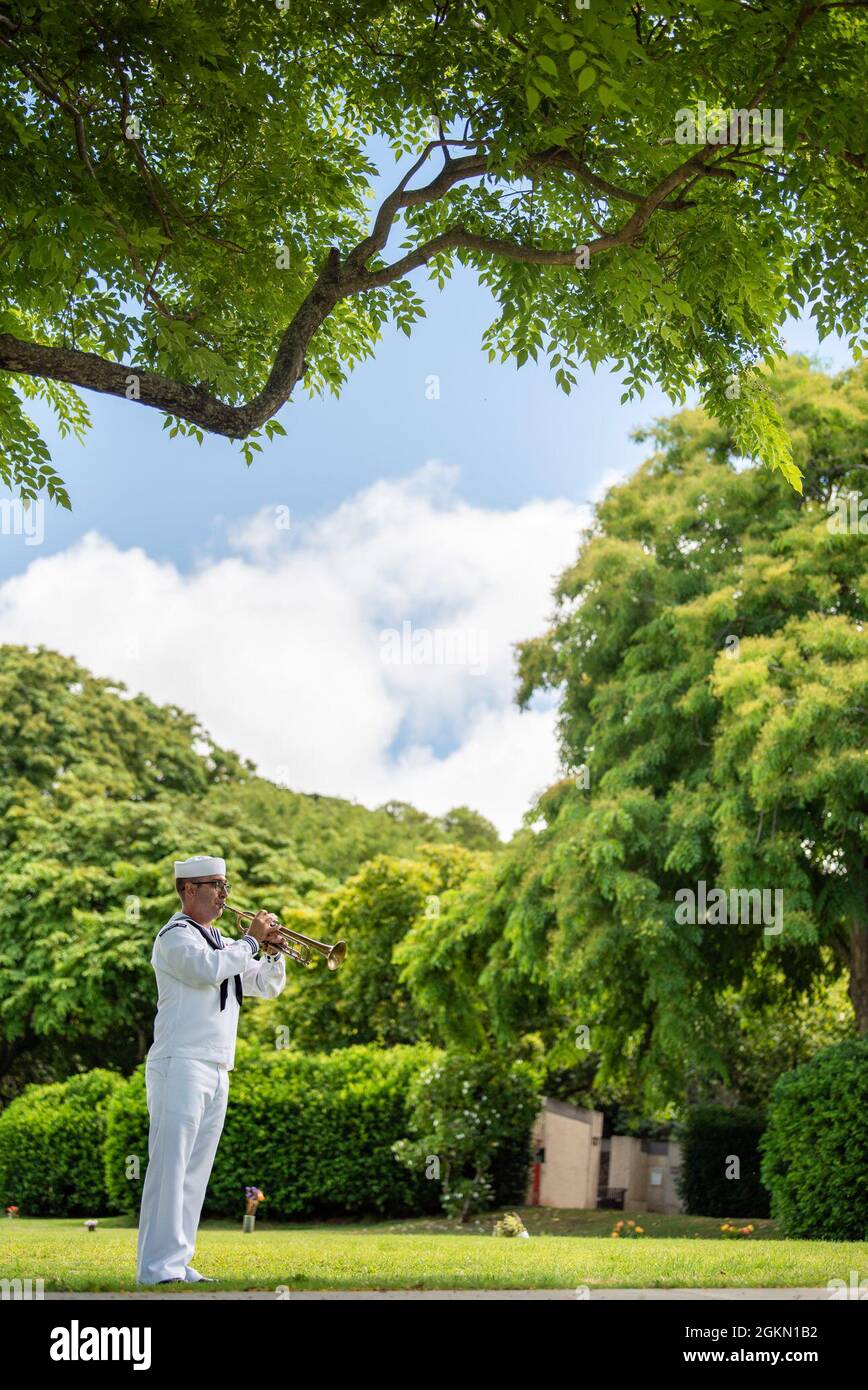 A bugler assigned to Navy Region Hawaii plays the bugle at a funeral for U.S. Navy Gunner’s Mate 3rd Class Shelby Treadway, 25, of Manchester, Kentucky, at the National Memorial Cemetery of the Pacific, Honolulu, Hawaii, June 2, 2021. Treadway was assigned to the USS Oklahoma, which sustained fire from Japanese aircraft and multiple torpedo hits causing the ship to capsize and resulted in the deaths of more than 400 crew members on Dec. 7, 1941, at Ford Island, Pearl Harbor. Treadway was recently identified through DNA analysis by the DPAA forensic laboratory and laid to rest with full militar Stock Photo