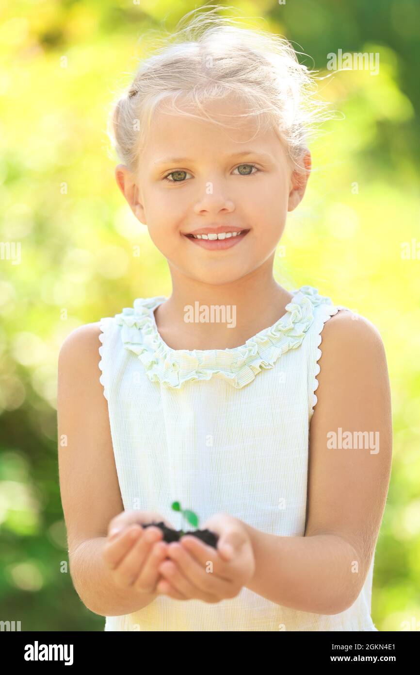 Cute girl holding green plant outdoors Stock Photo - Alamy