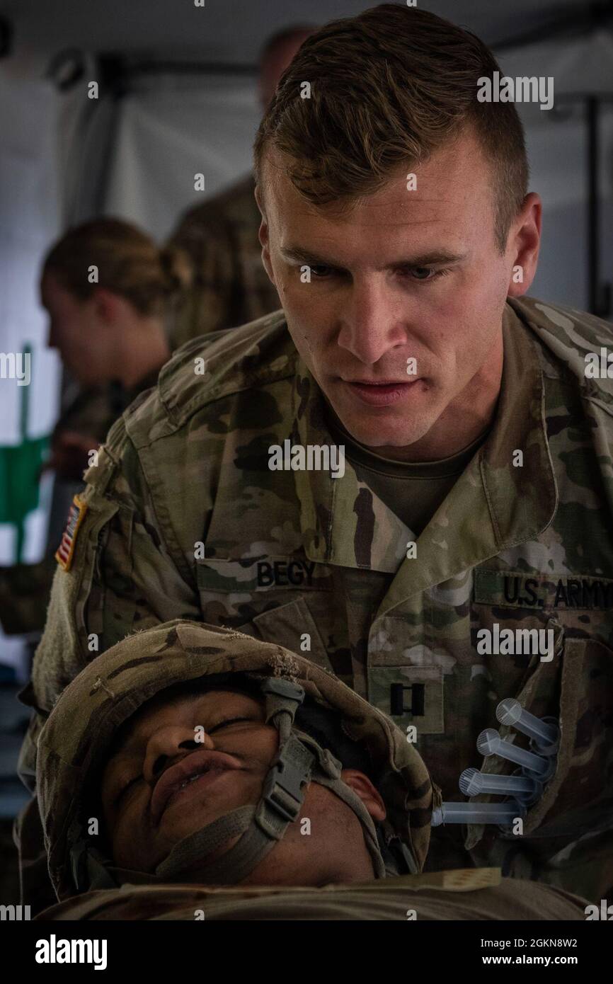 U.S. Army Capt. Colin Begy, battalion surgeon with 557th Medical Company Area Support triages a simulated casualty at a role 2 care facility during Hospital Exercise 21 at Baumholder, Germany June 3, 2021. The 30th Medical Brigade deployed over 400 Soldiers in support of Hospital Exercise 21 which served to certify the 519th Hospital center as a NATO role 2 enhanced capability. The 30th MED BDE treated over 100 simulated patients from the point of injury to medical evacuation to higher echelons of care. The exercise also enhanced joint, combine and multi echelon interoperability. Stock Photo