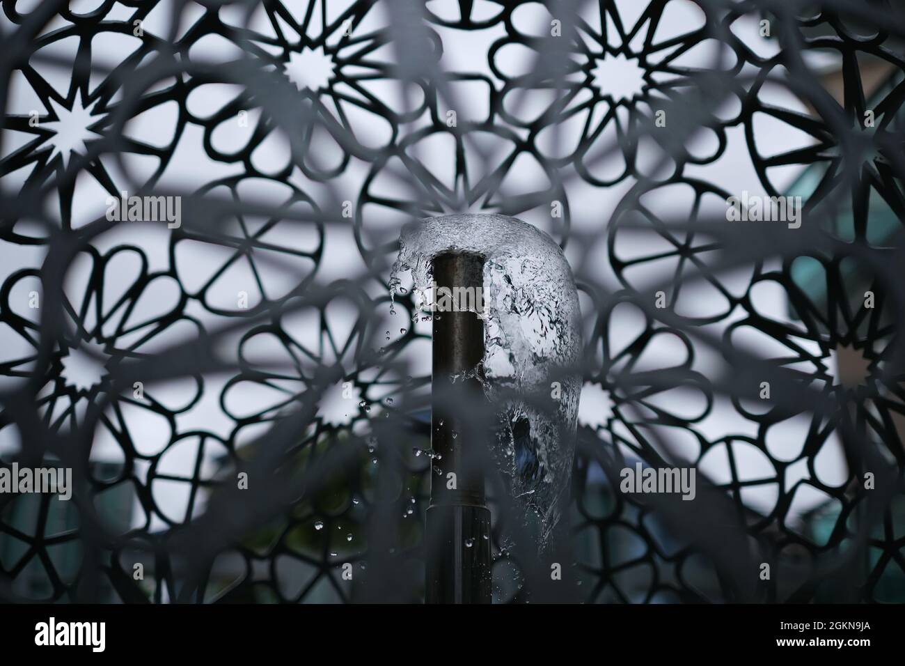 An outdoor fountain inside metal tracery dome Stock Photo