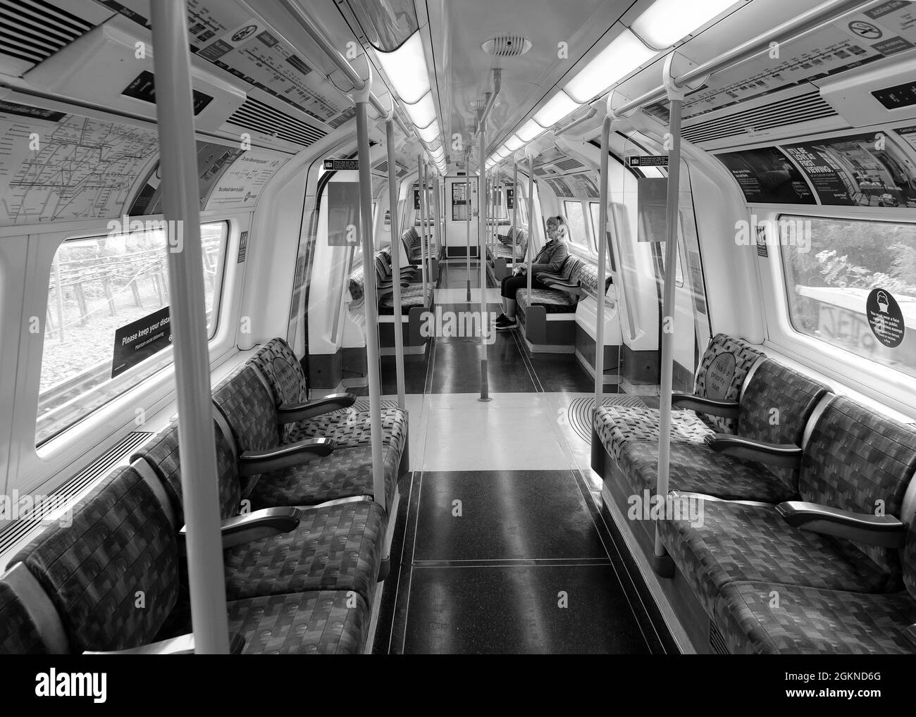 Black and White image of a Lady sitting on her own in an empty London tube train giving a feeling of isolation Stock Photo