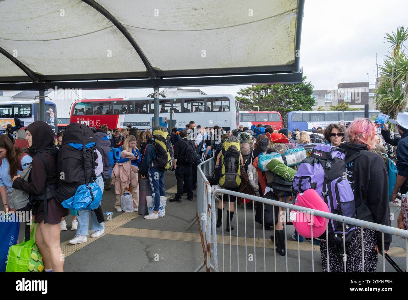 Young people carrying heavy rucksacks queueing for buses to take them to the opening day of The Boardmasters Festival in Cornwall. Stock Photo