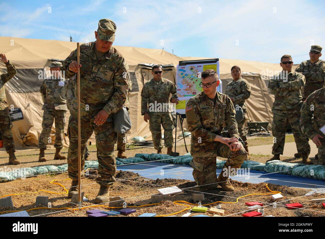 U.S. Army Reserve Maj. Richard Flores, 358th Civil Affairs Brigade, gets an assist from Spec. Kyle Moller, a Civil Affairs Specialist with the 364th Civil Affairs Brigade and augmentee to the exercise S2 section as they brief the change in phases during the rehearsal of concept brief at Command Post Exercise – Functional (CPX-F) 21-02, June 5, 2021, at Ft. McCoy, Wis. CPX-F brings units from across the command together to work in cooperation in an exercise scenario that mirrors real-world mission concerns. Stock Photo
