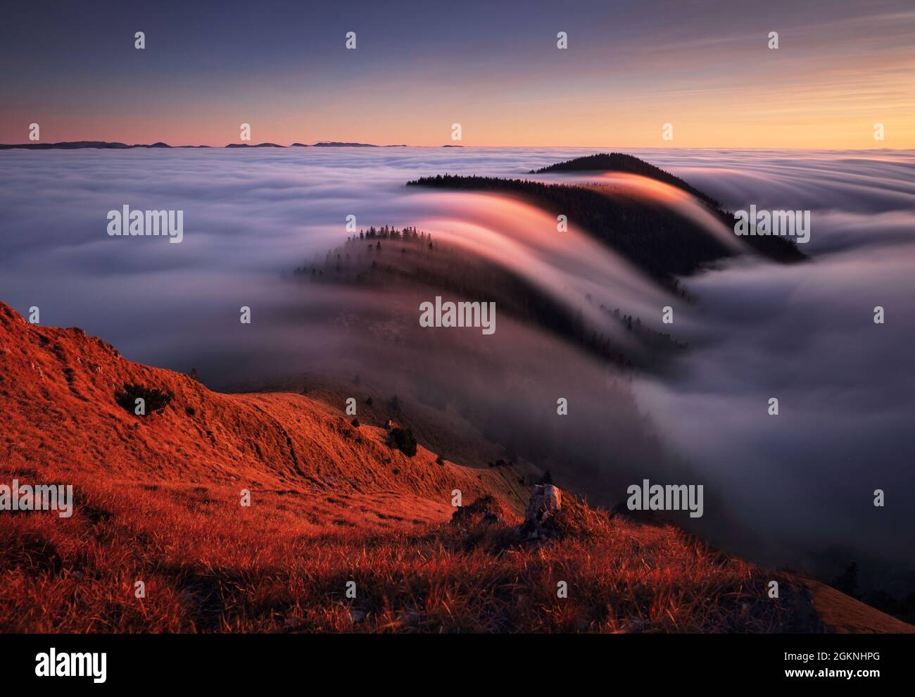 Mountain landscape above clouds at sunset in Slovakia with forest and sun Stock Photo