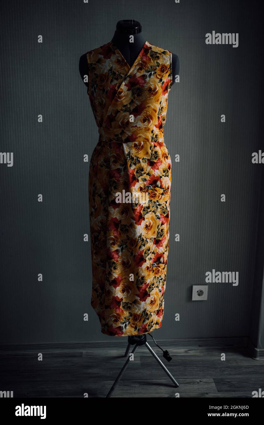 yellow-red dress made of natural fabric on a mannequin. photo of clothes in the atelier. smooth seams and stitches are stitched with thread. the seams Stock Photo