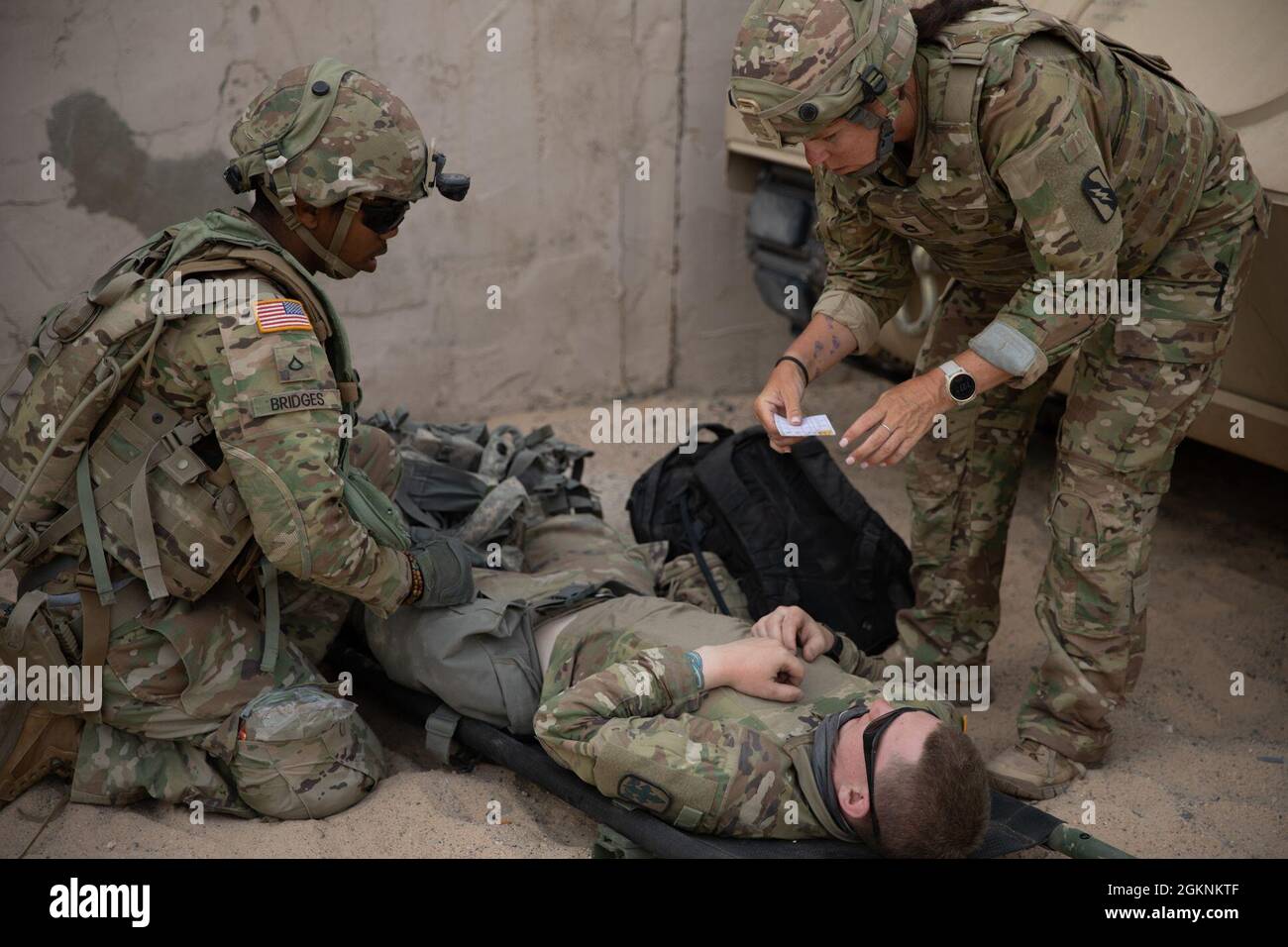 A medic with the 1037th Engineer Company, Arkansas Army National Guard, evaluates a simulated casualty using a casualty card during combat training at the National Training Center, Fort Irwin, California June 7, 2021. Casualty cards are used in training to describe battlefield injuries that prompt medical personnel to demonstrate their ability in treating Soldiers in the field. The 1037th is at NTC to support the 155th Armored Brigade Combat Team in readiness and interoperability training. Stock Photo