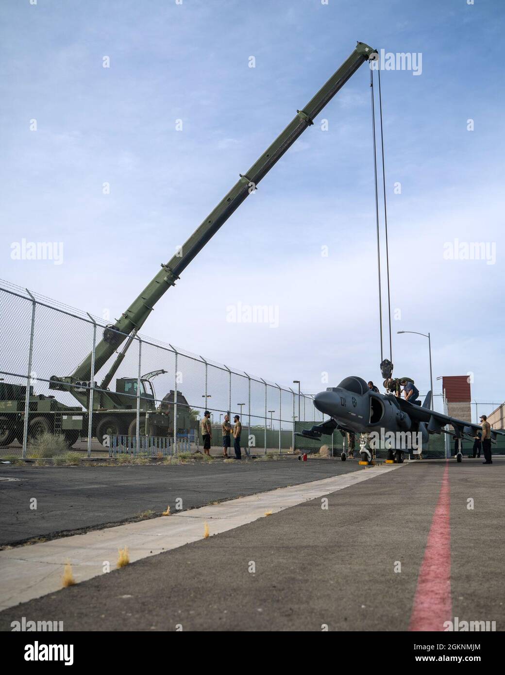 An AV-8B Harrier jet is lifted over a gate on Marine Corps Air Station Yuma, June 7, 2021. The Harrier is now a static display near the entrance of the Air Station. Stock Photo