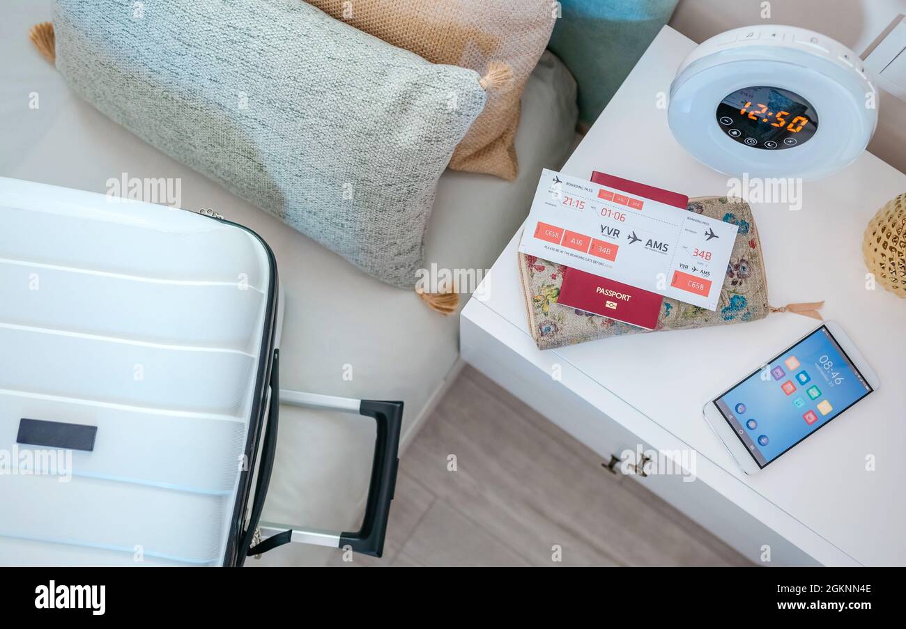 Suitcase on the bed and air ticket on the bedside table Stock Photo