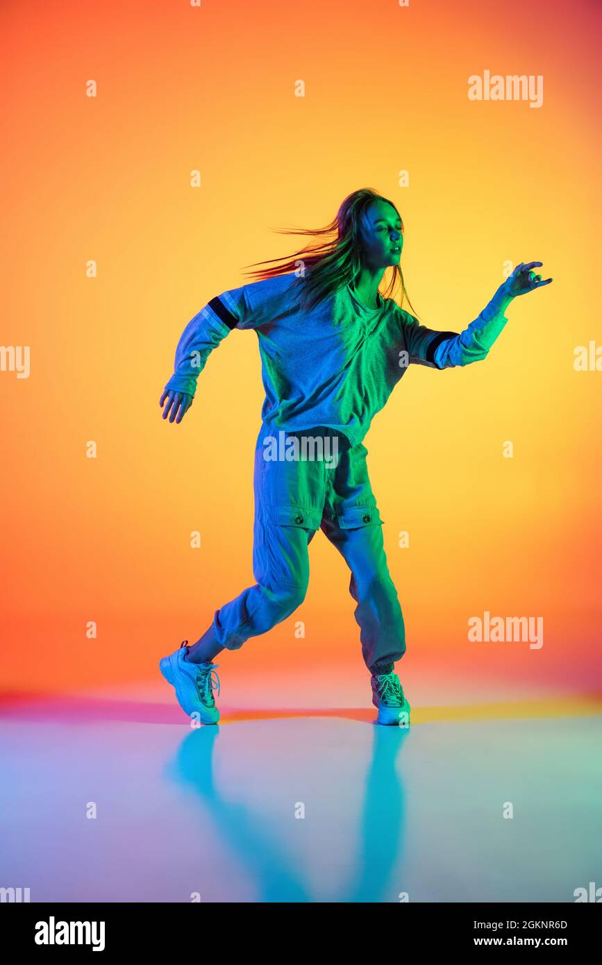Young sportive girl dancing hiphop in stylish clothes on colorful