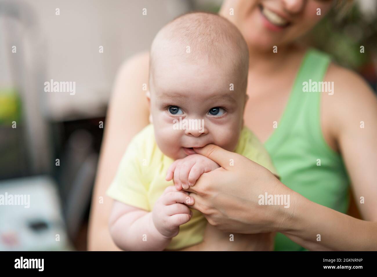 Portrait of cute little baby boy holding mother's finger in his mouth